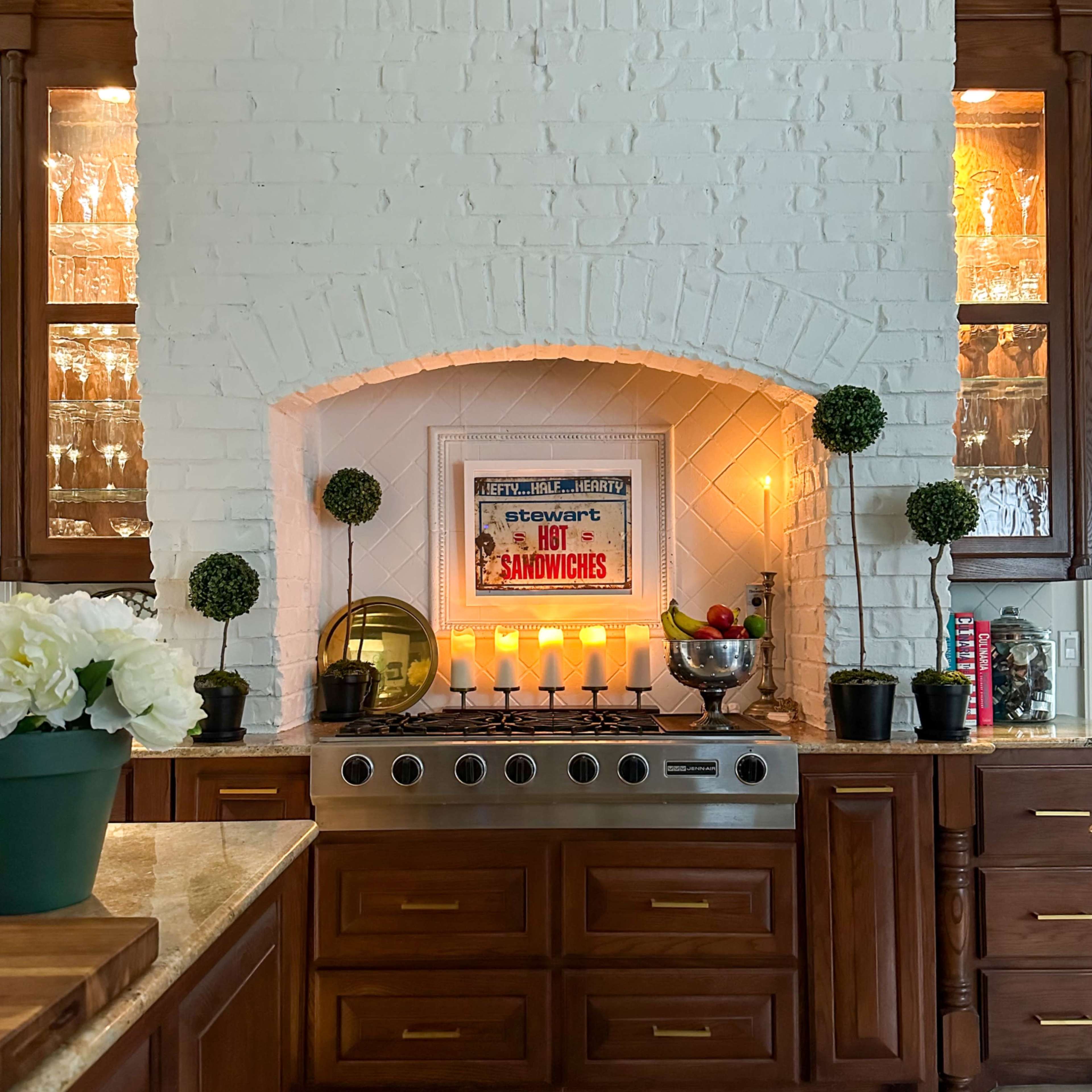 A kitchen features a white brick alcove with a stove, decorative items, and candlelight.
