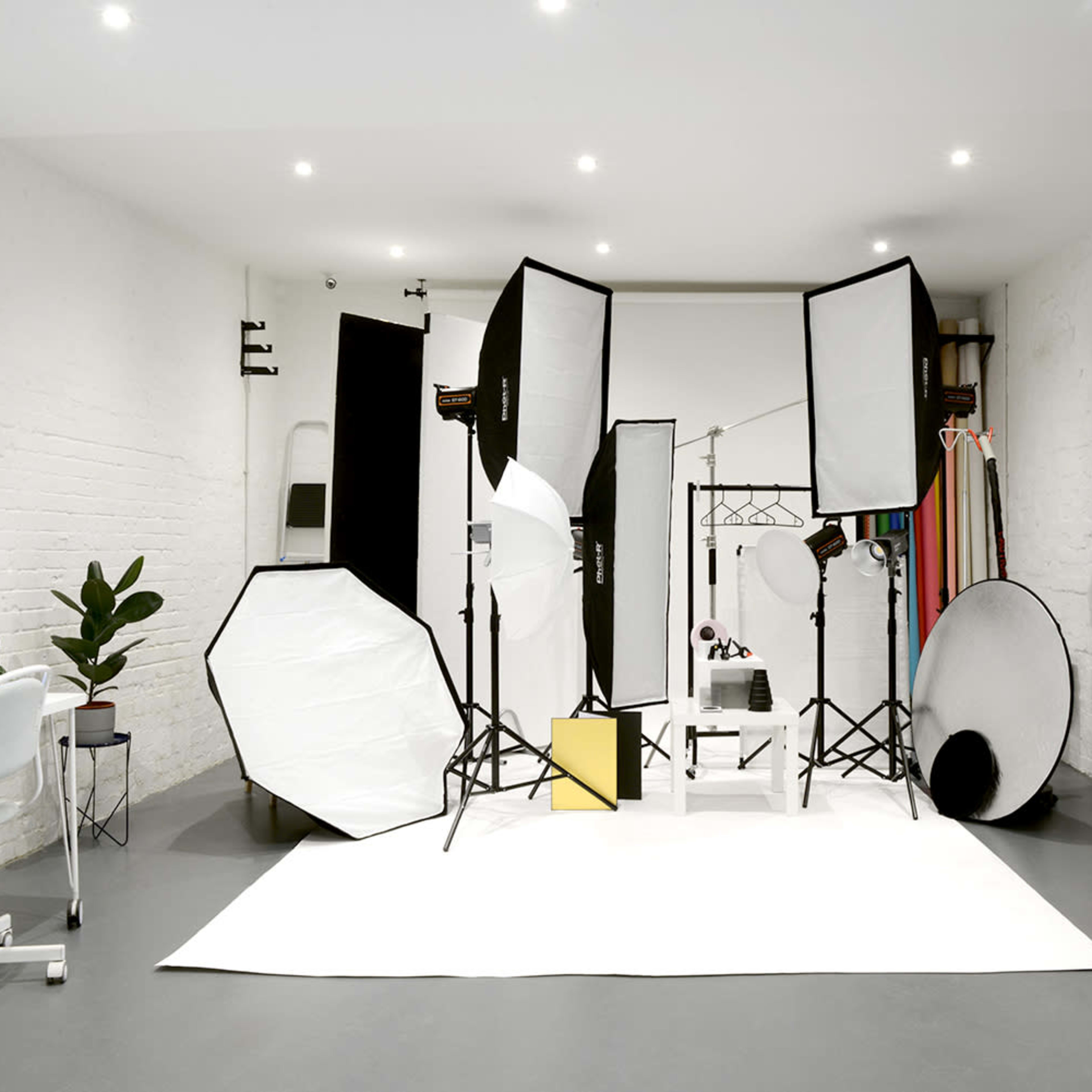 A photography studio is set up with various lighting equipment and backdrops arranged on a white backdrop.