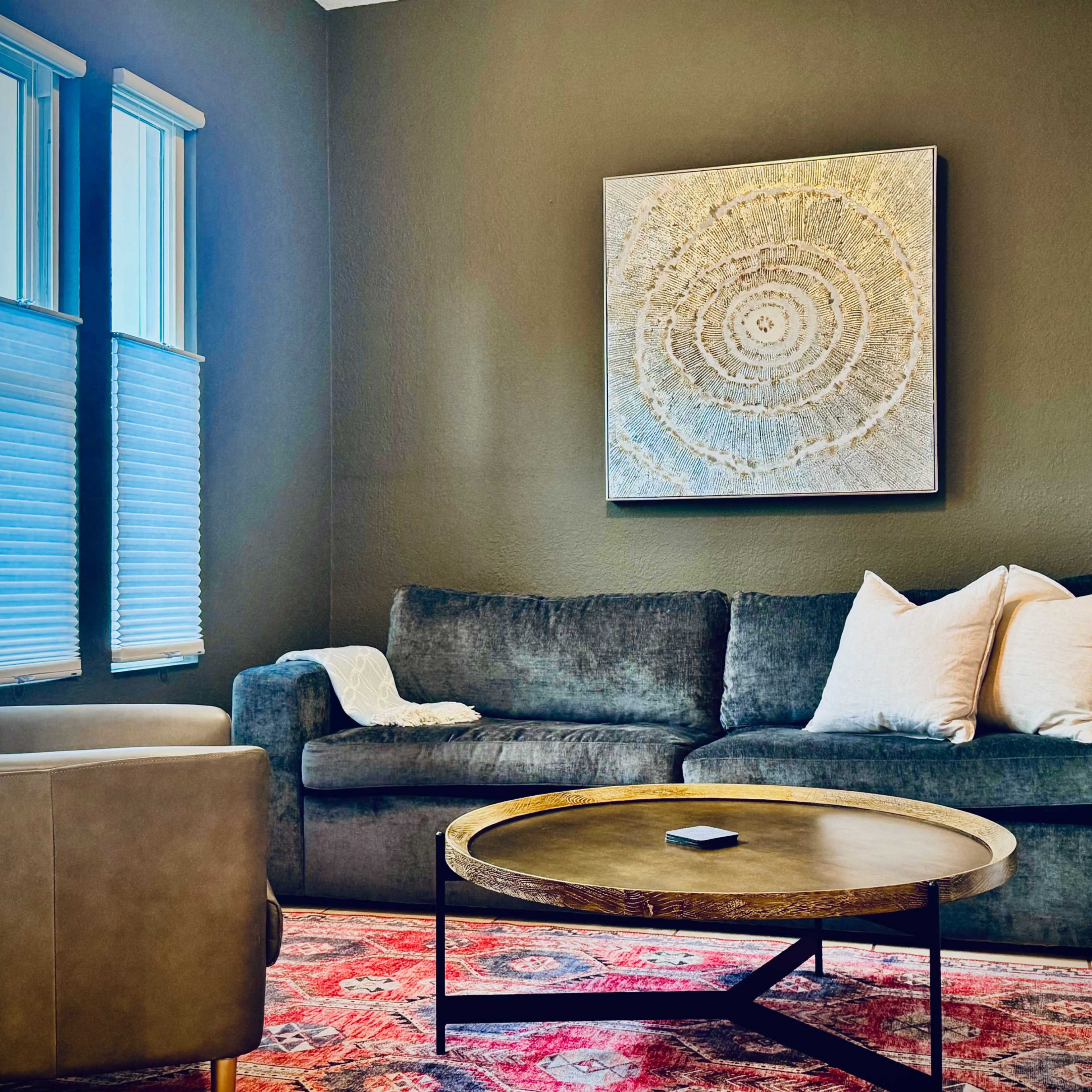 A living room with a gray sofa, two white decorative pillows, a round coffee table, and a patterned rug.