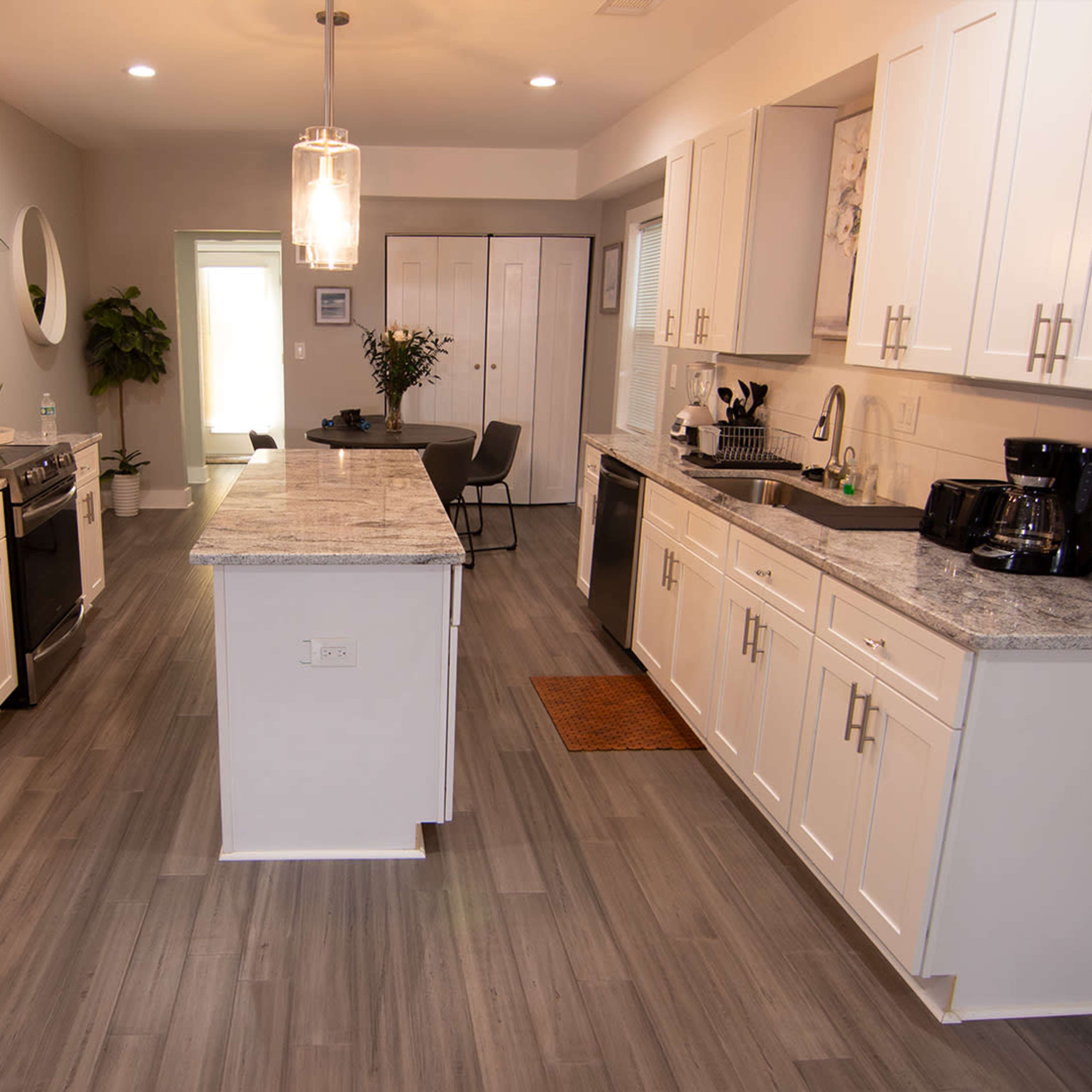 A modern kitchen features stainless steel appliances, white cabinetry, and a central island with a gray countertop.