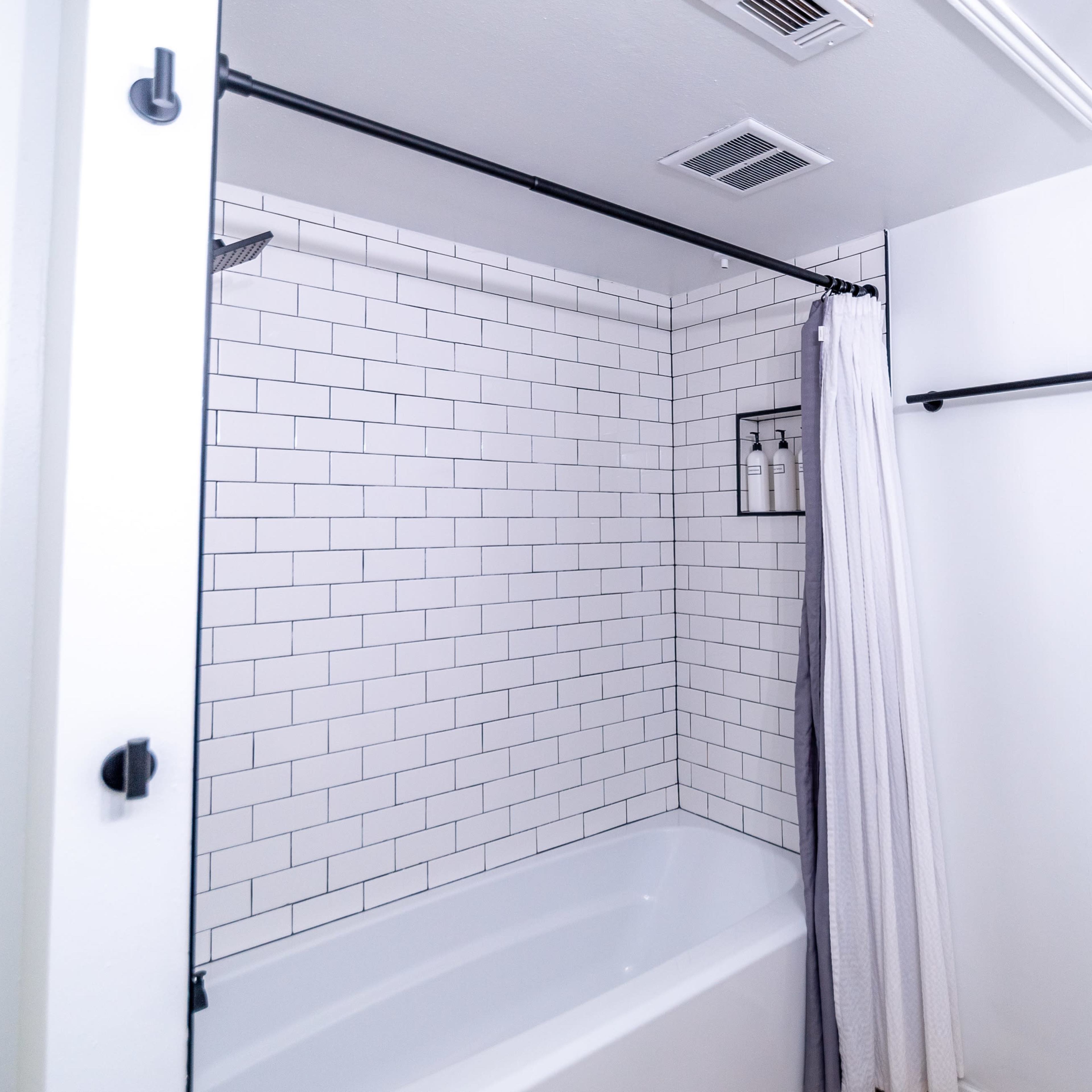A bathroom featuring a bathtub with a tiled wall, a shower curtain, and a towel bar.