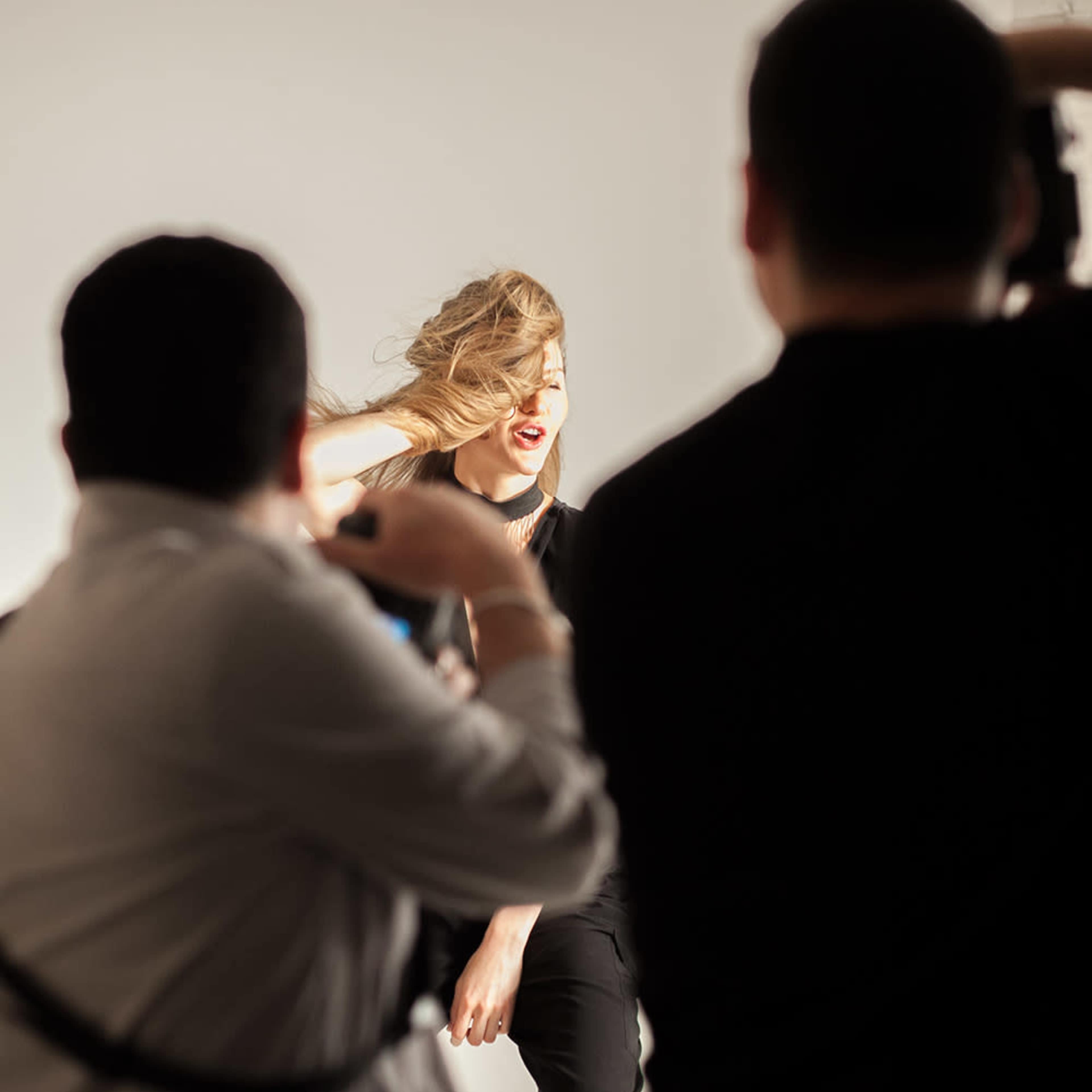A model poses in a studio while photographers capture her image.