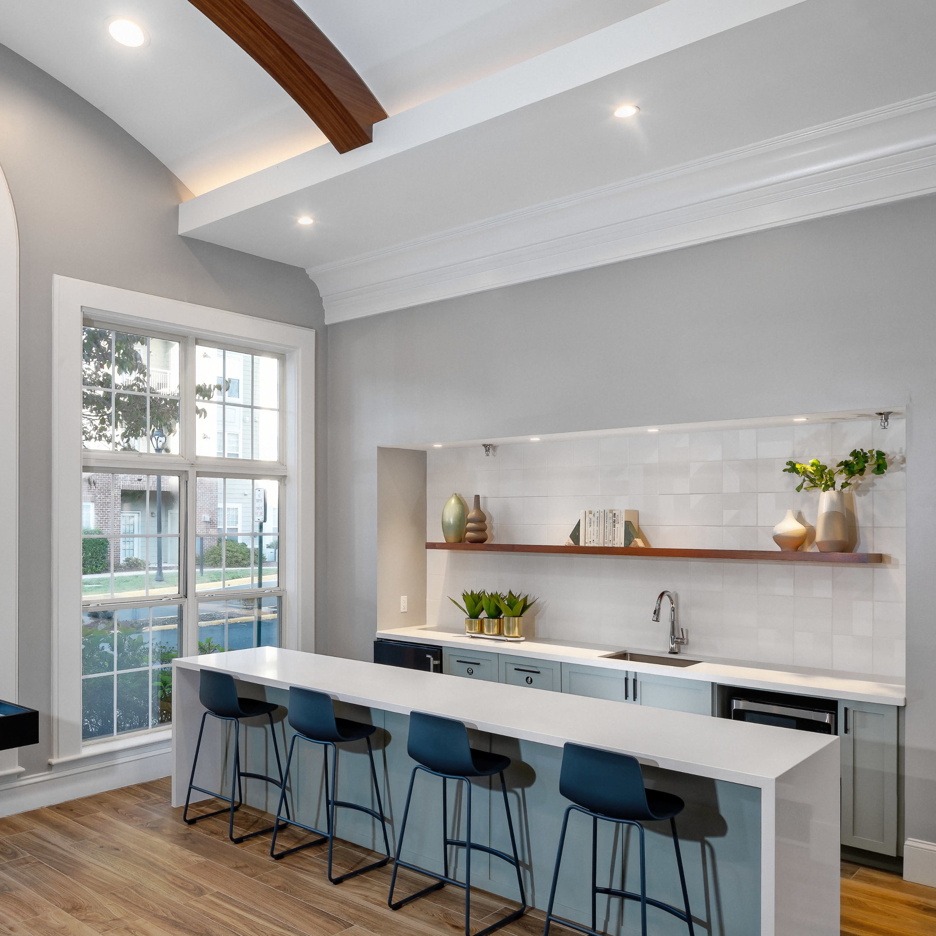 A modern kitchen with a large island, bar stools, and a window that allows natural light to fill the space.