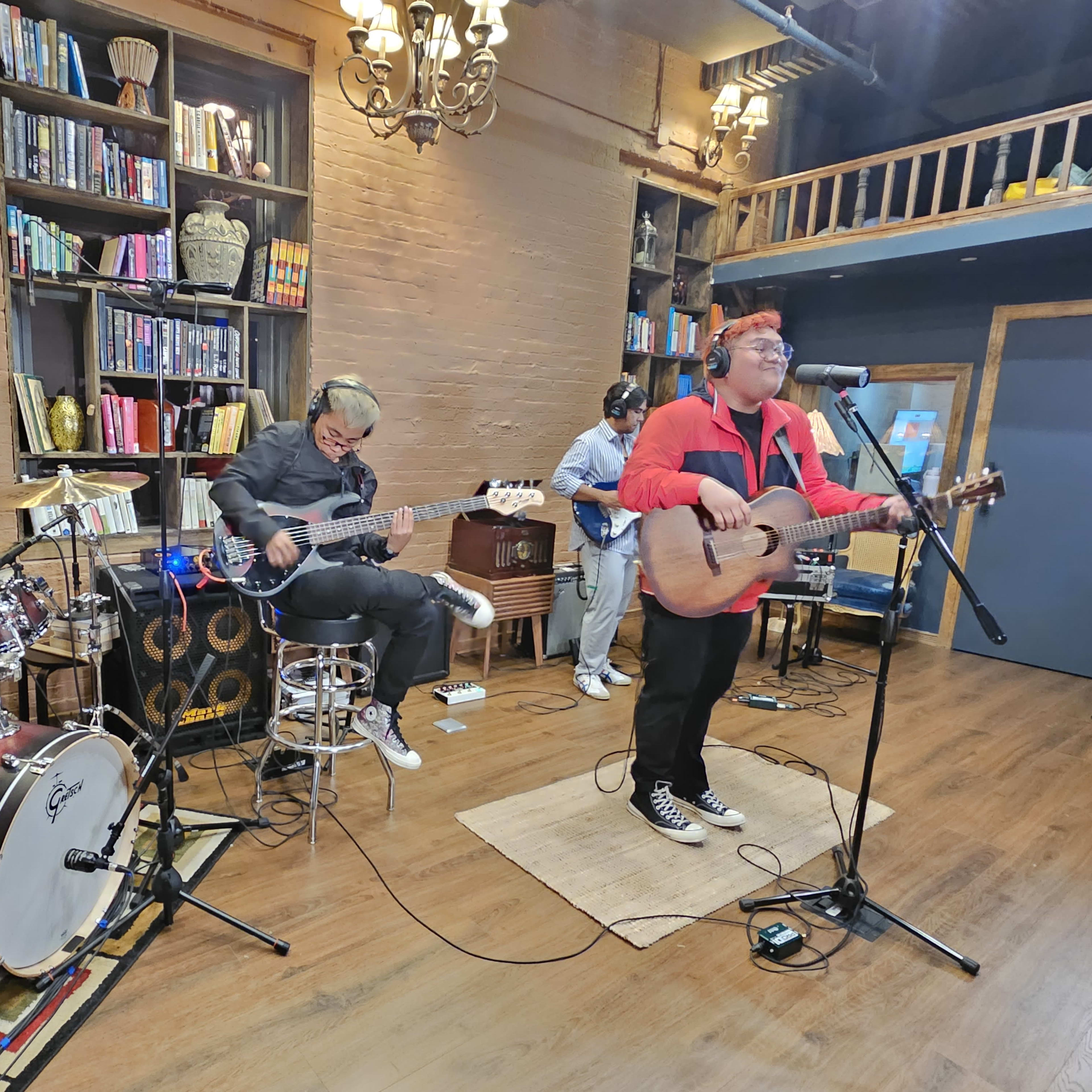 A band performs live music in a cozy venue surrounded by bookshelves.