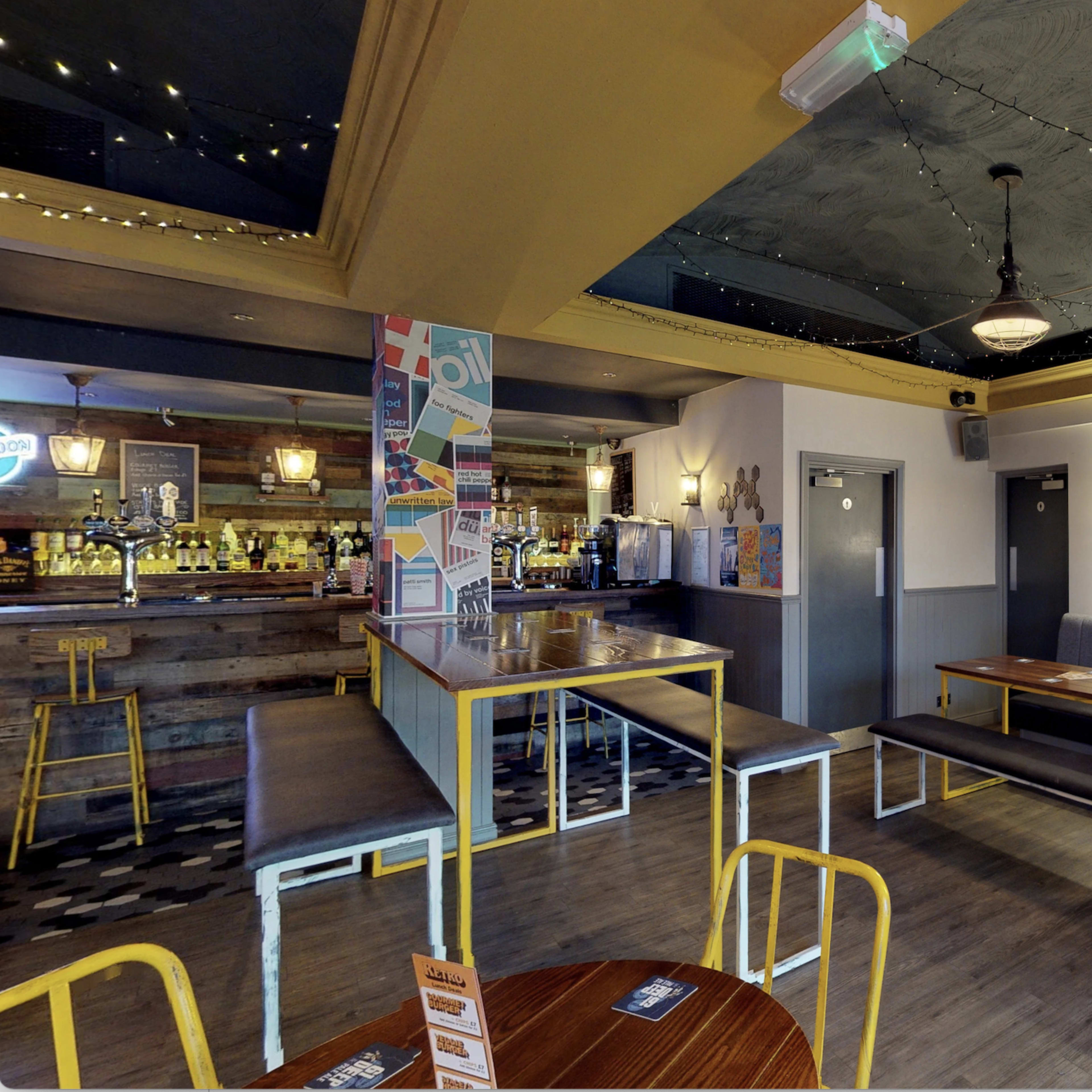 The interior of a bar with seating areas, a bar counter, and decorative lighting.