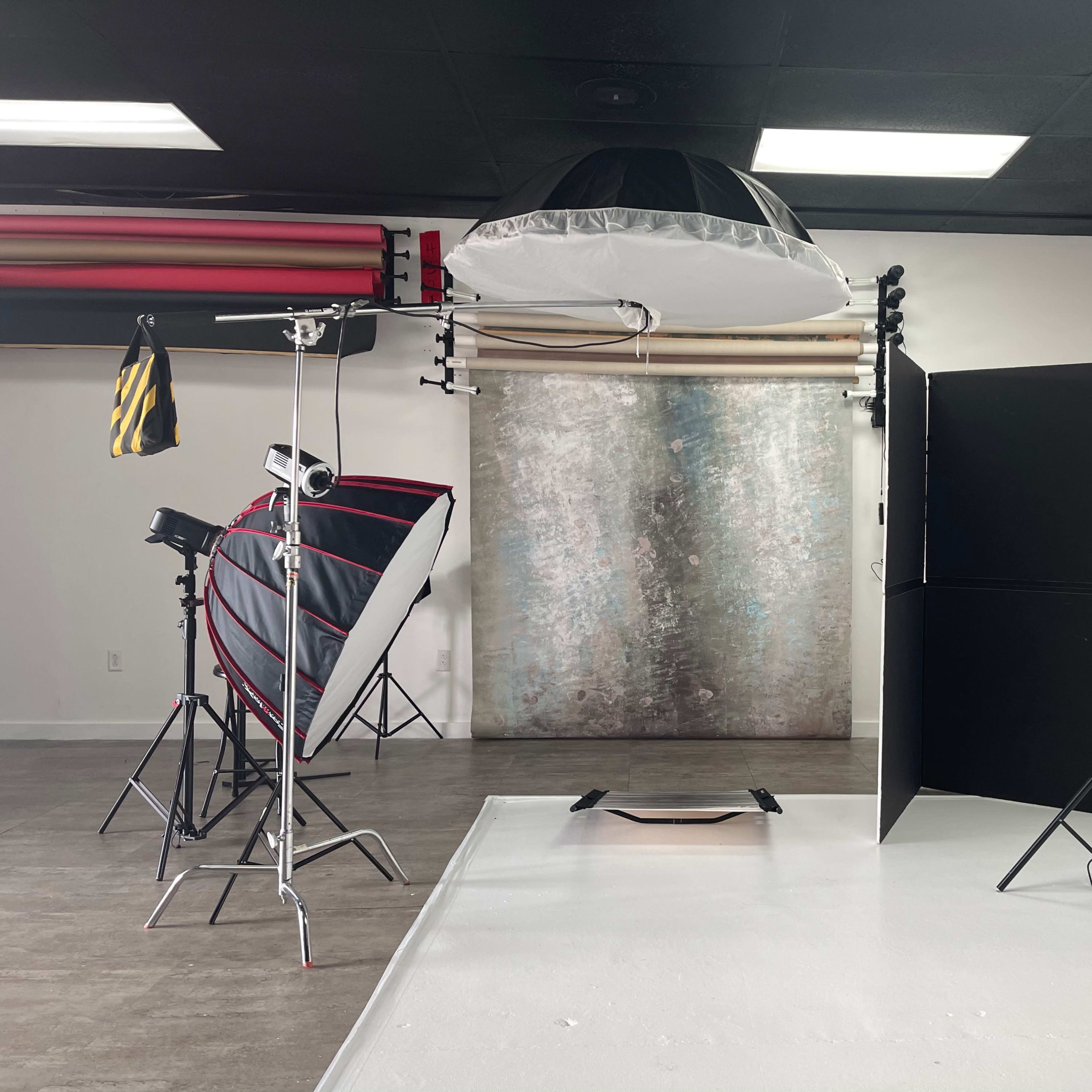 A photography studio setup featuring multiple light sources, backdrops, and a reflective umbrella.