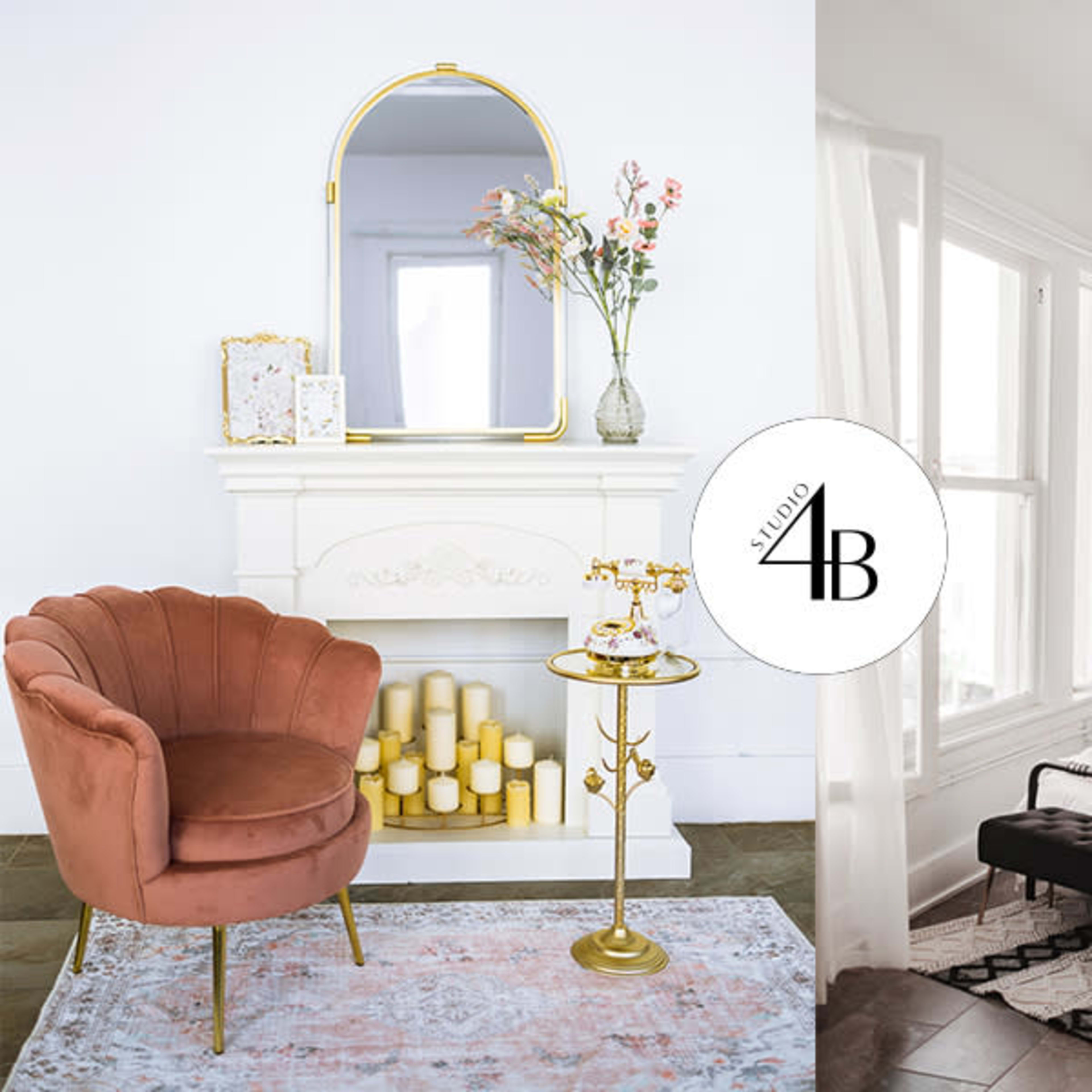 A split scene: on one side, a living space with a pink velvet armchair and a decorative fireplace adorned with flowers and candles; on the other side, a bedroom with a black metal bed frame and large windows allowing natural light.