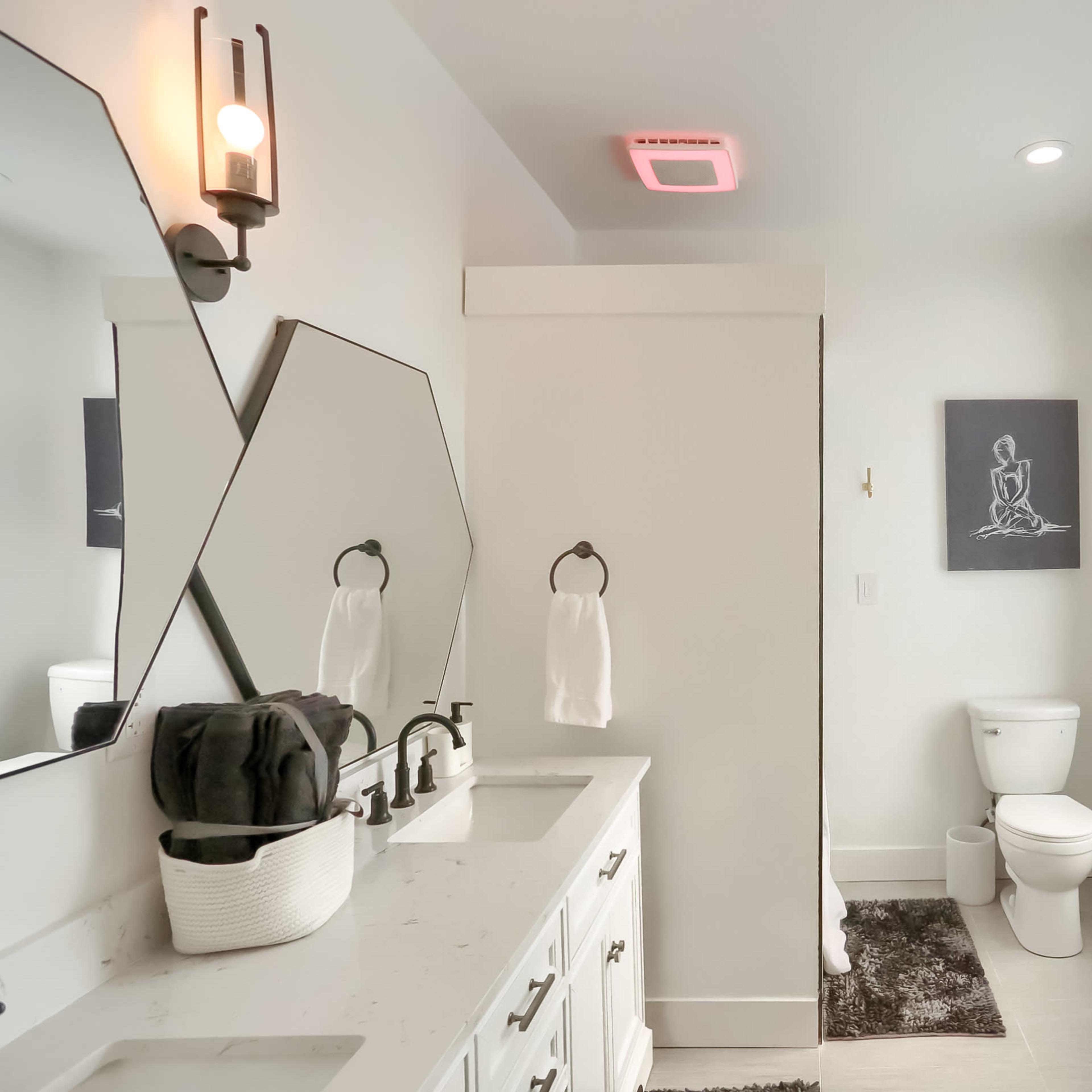 A modern bathroom with a double sink vanity, a freestanding bathtub, and a framed artwork on the wall.
