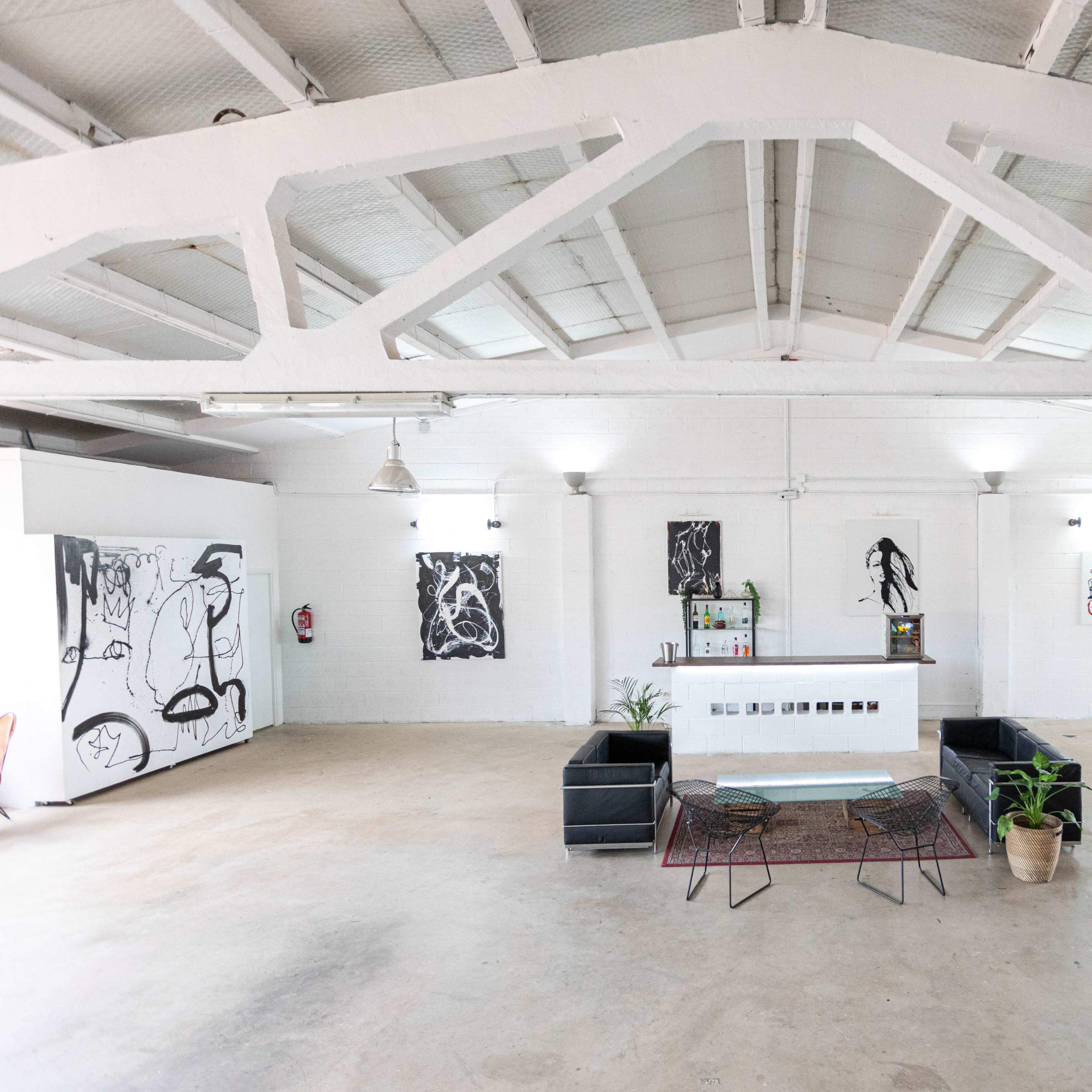 A spacious, minimalist interior of an art gallery with a reception area featuring a seating arrangement and walls adorned with contemporary artwork.
