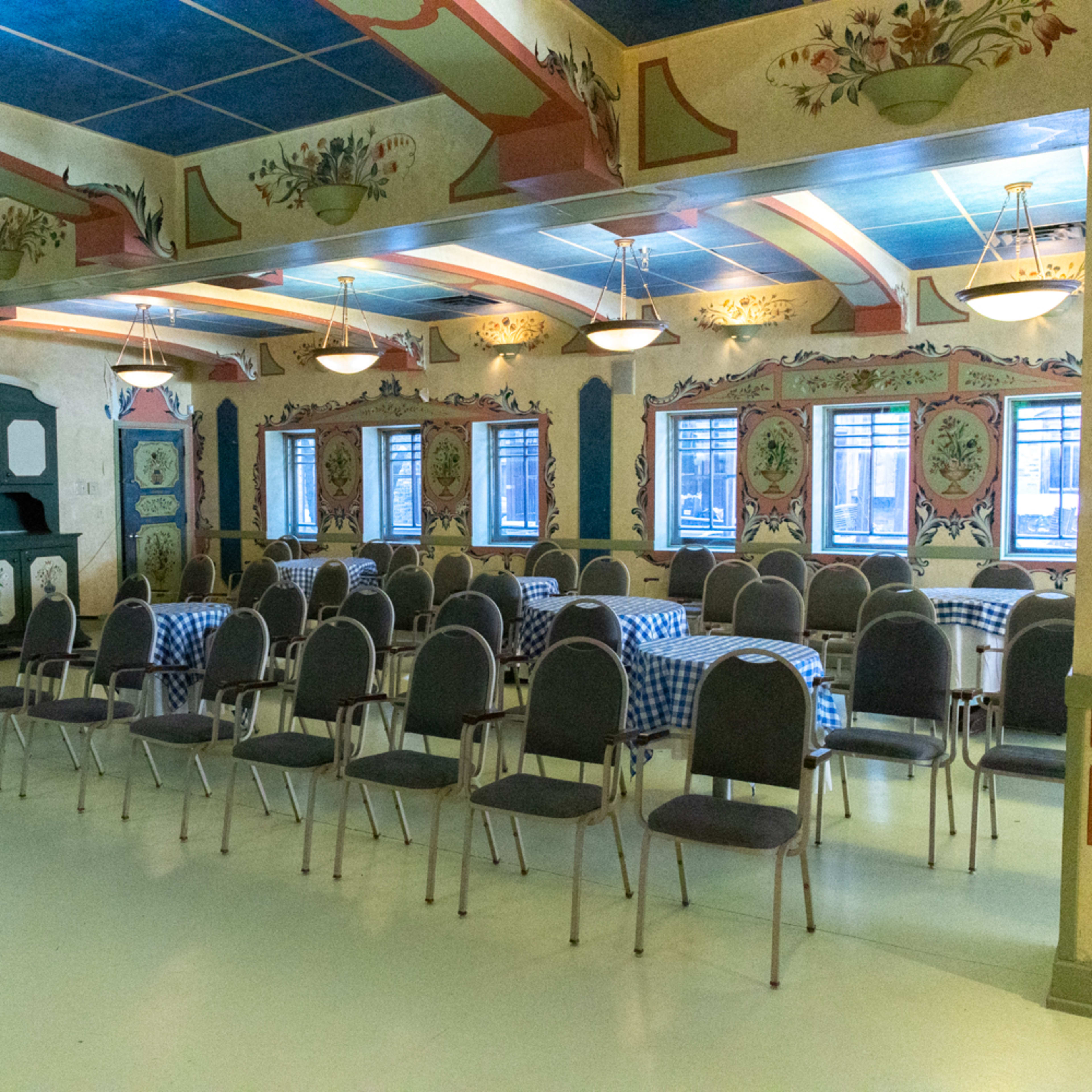 The room features rows of chairs arranged facing a decorated wall with floral patterns and a blue ceiling.