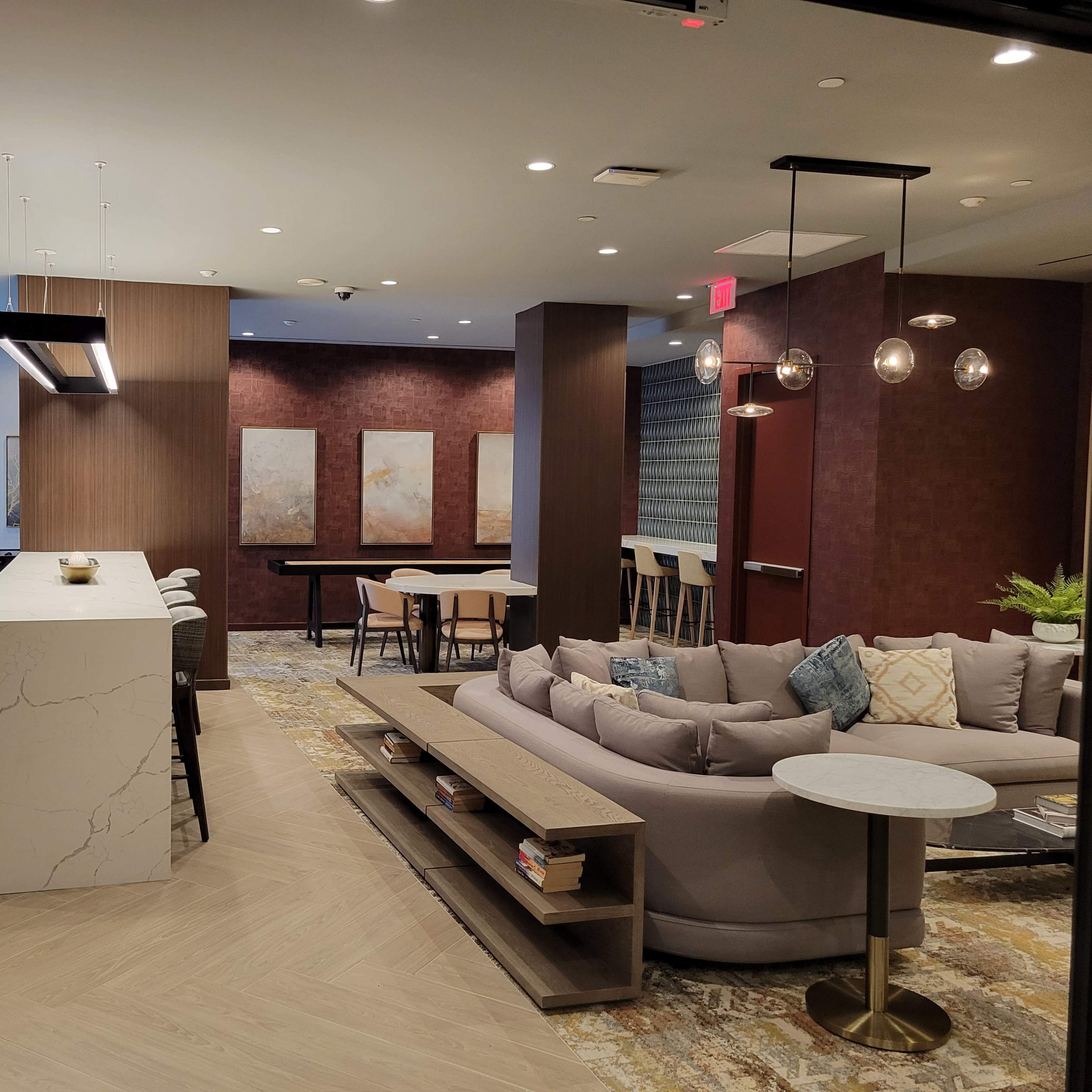 A modern, open-concept lounge area with a kitchen island, seating spaces, and decorative artwork on the walls.