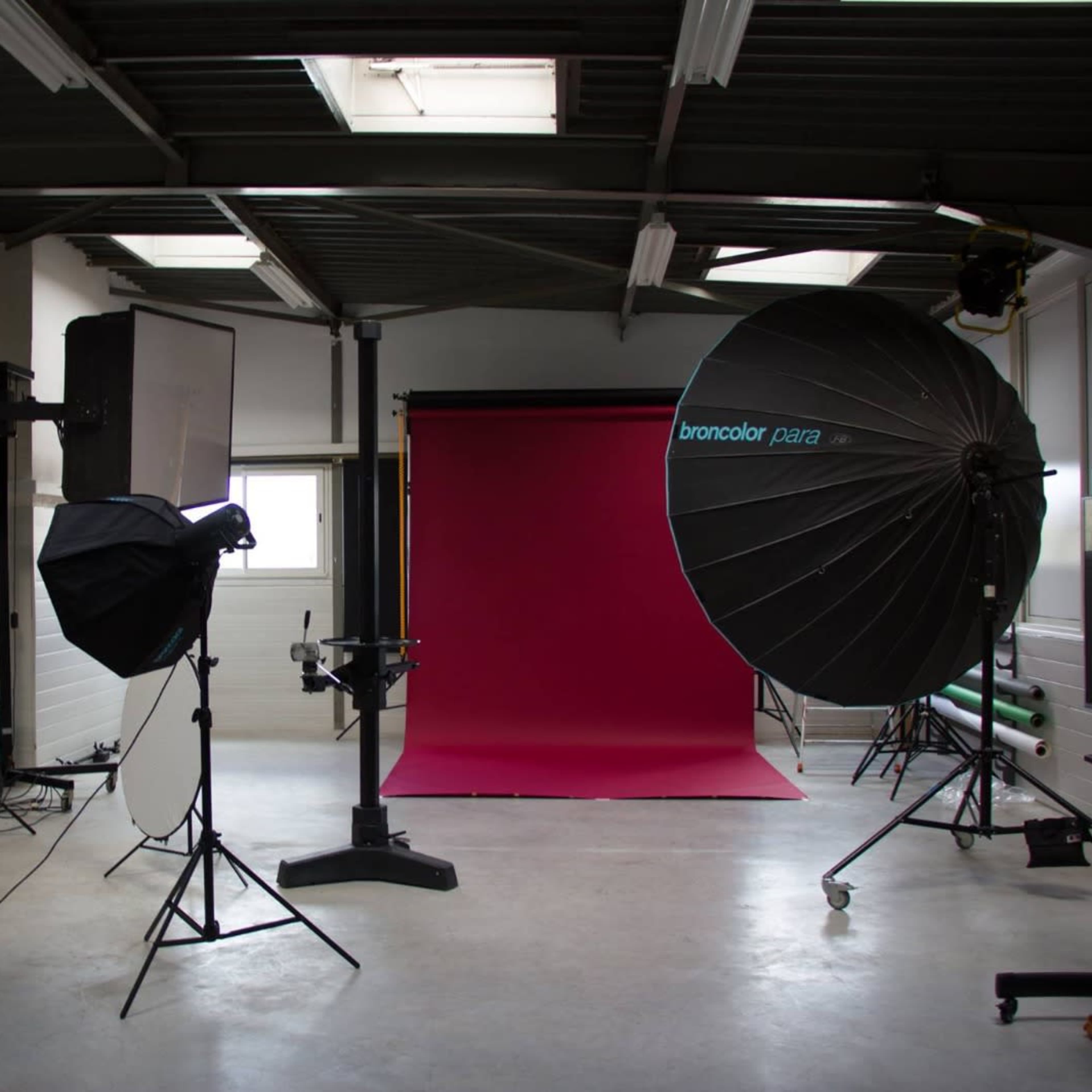 A photography studio is set up with various lighting equipment and a pink backdrop.
