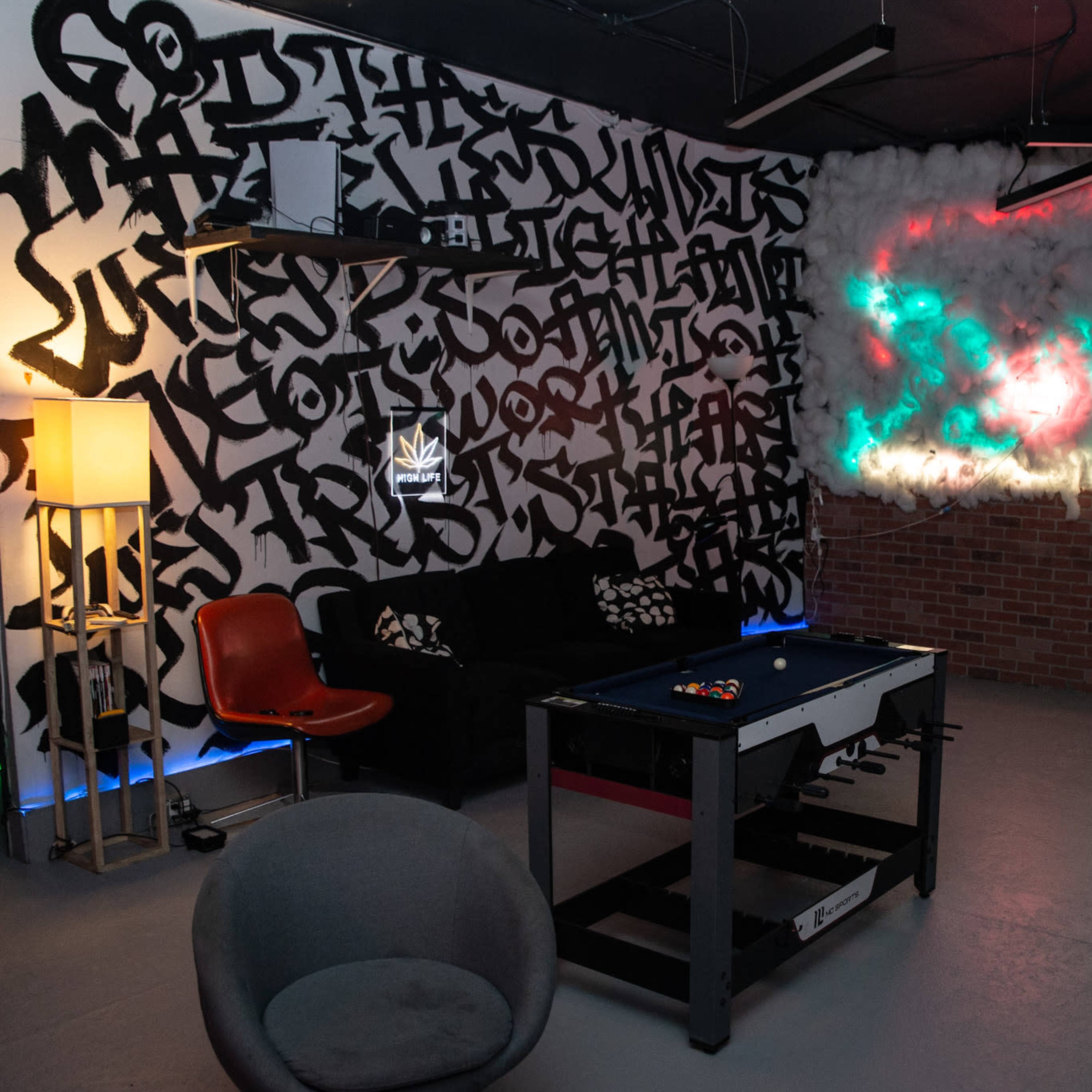 A recreational room with a pool table, colorful wall art, and a retro arcade machine.
