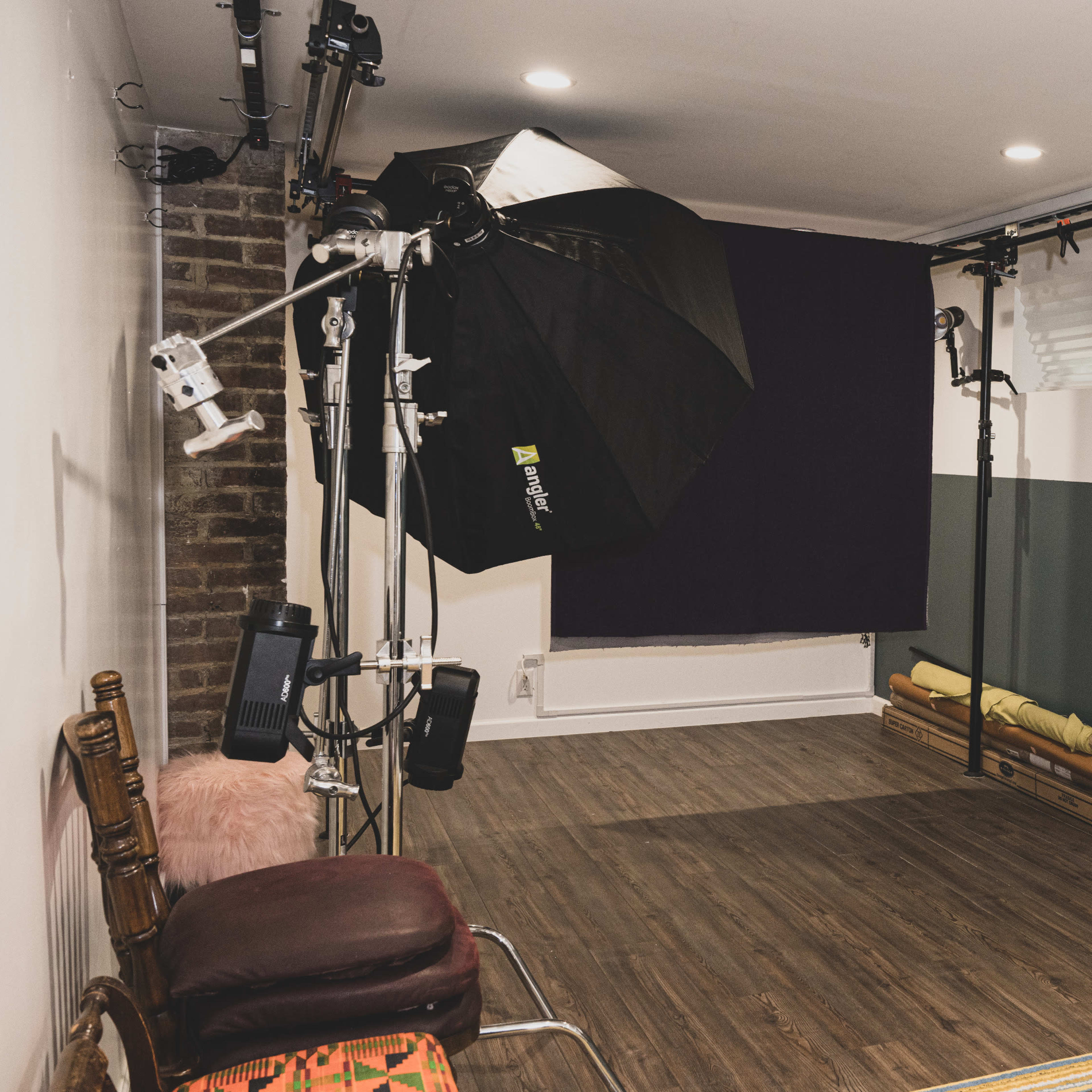 A photography studio with a lighting setup, backdrop, and various equipment arranged in a modern interior space.