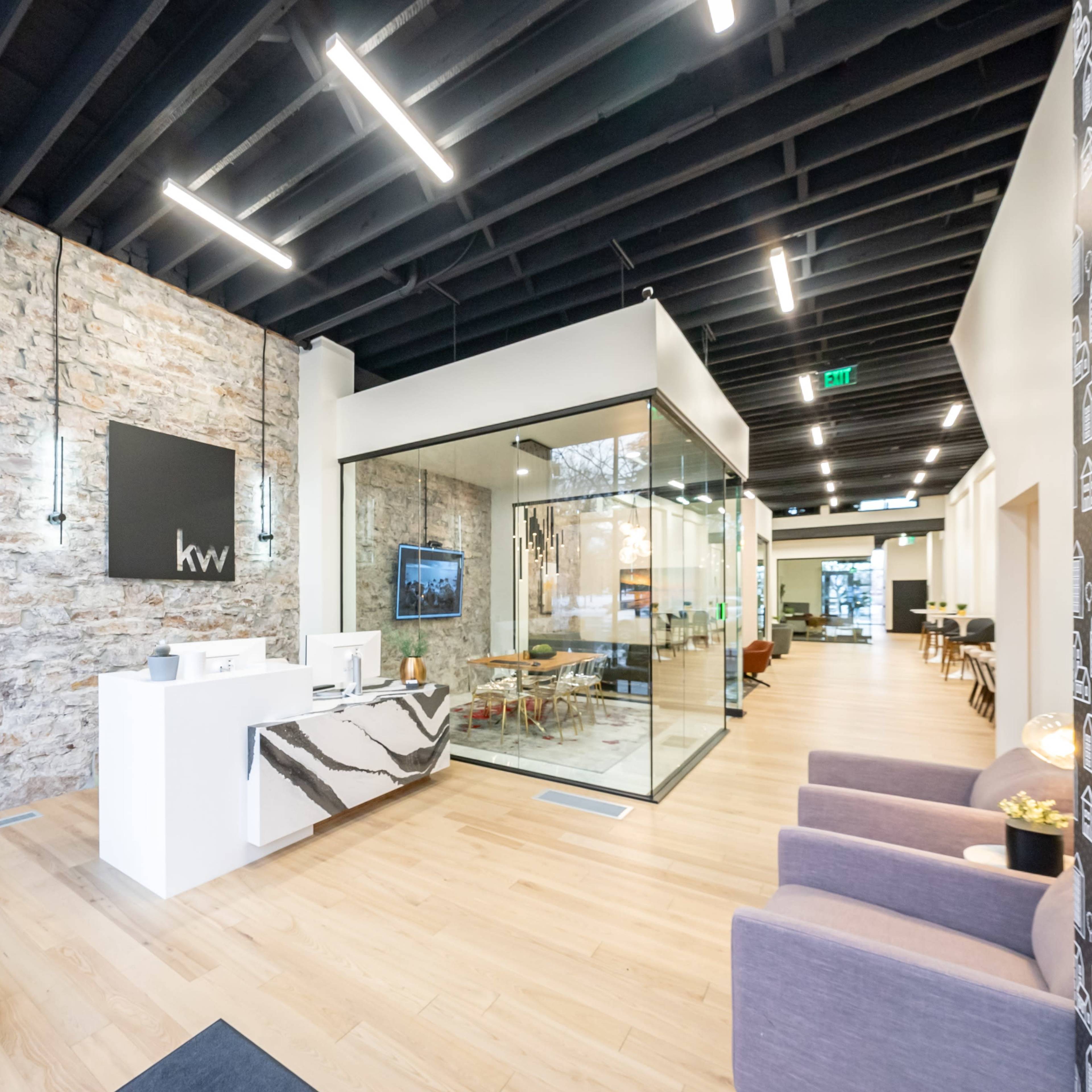 A modern office lobby with a stone wall, a reception desk, and a glass conference room.