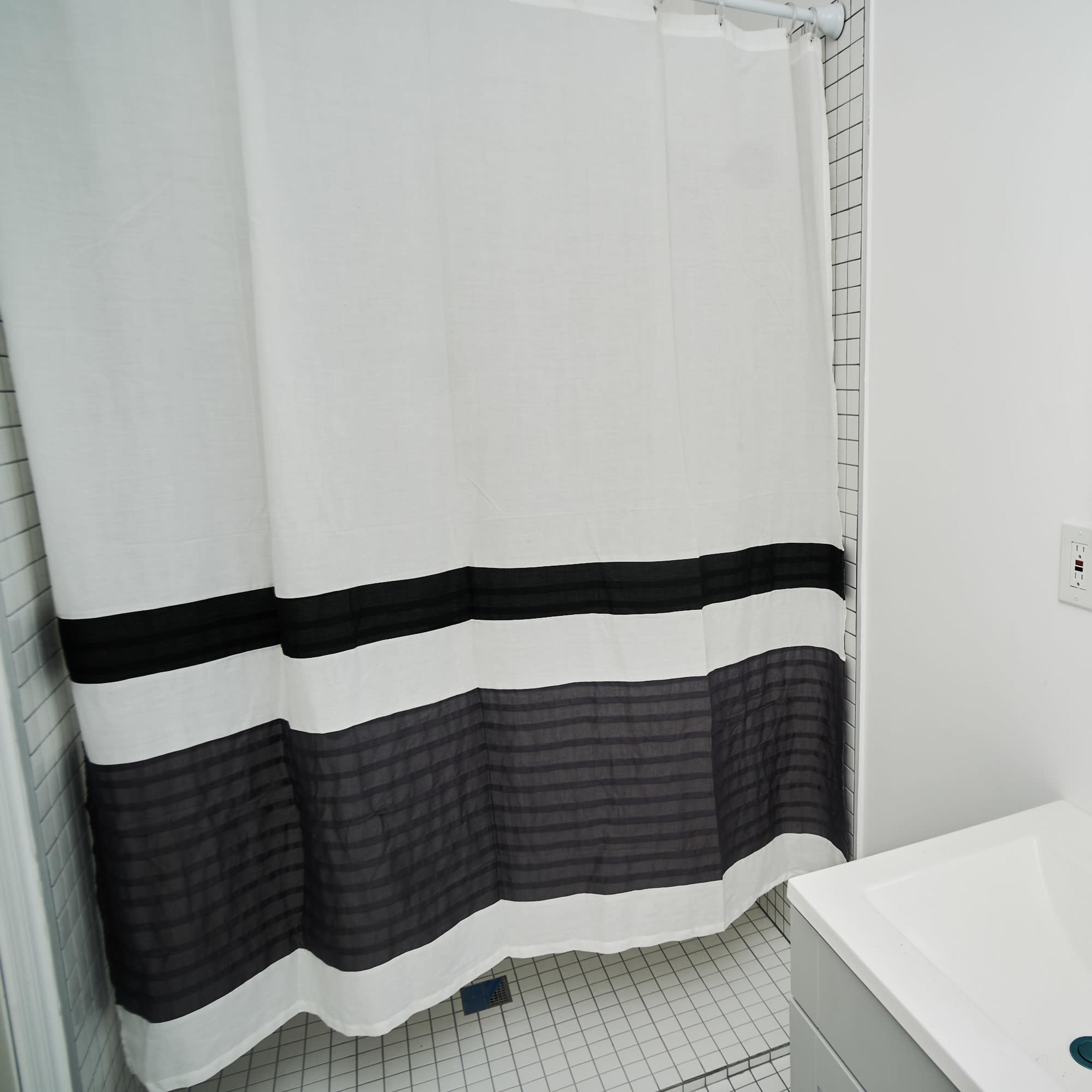 A bathroom with a shower curtain, a sink, and a mirror.