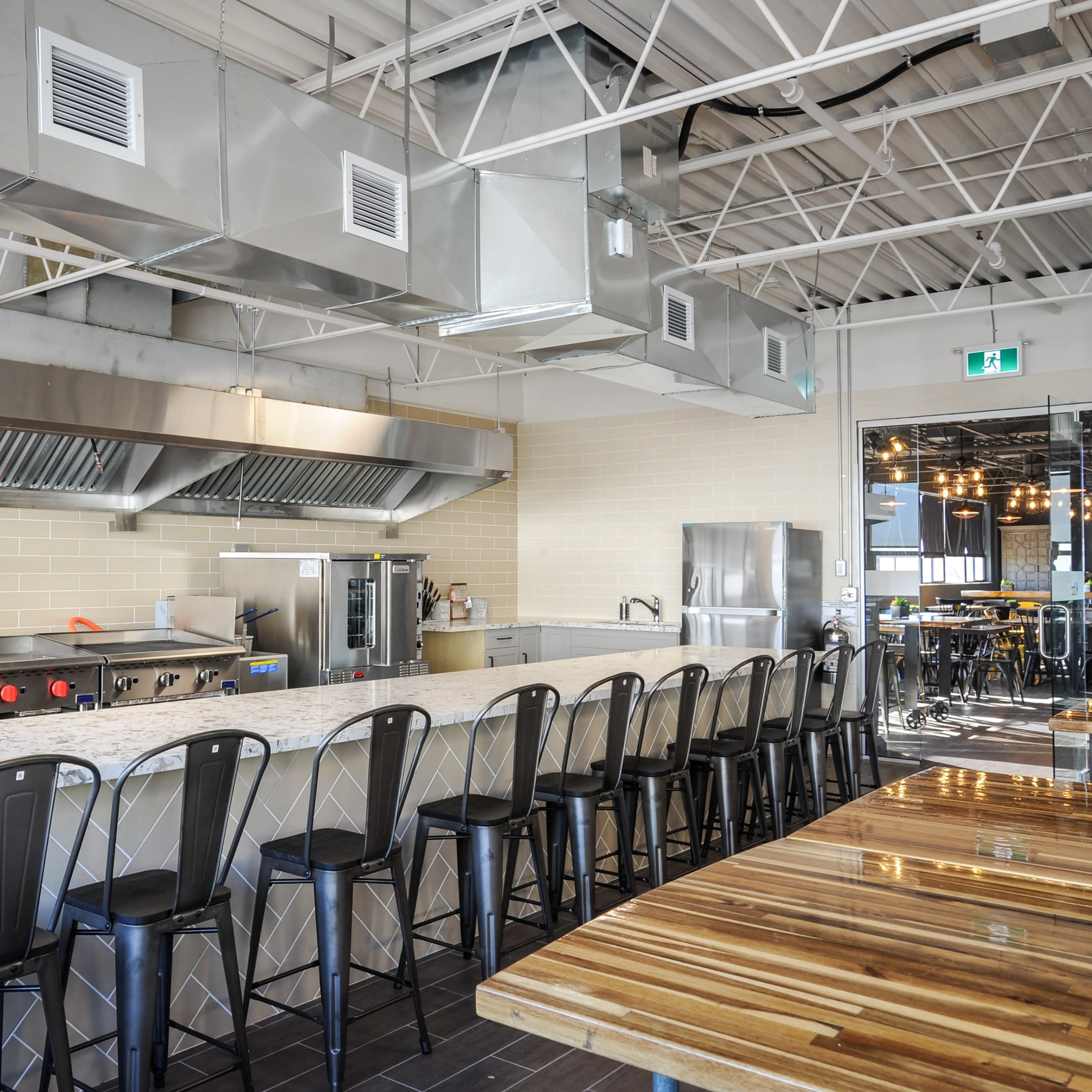 A modern kitchen with stainless steel appliances, a large central island, and sleek bar stools lining the counter.