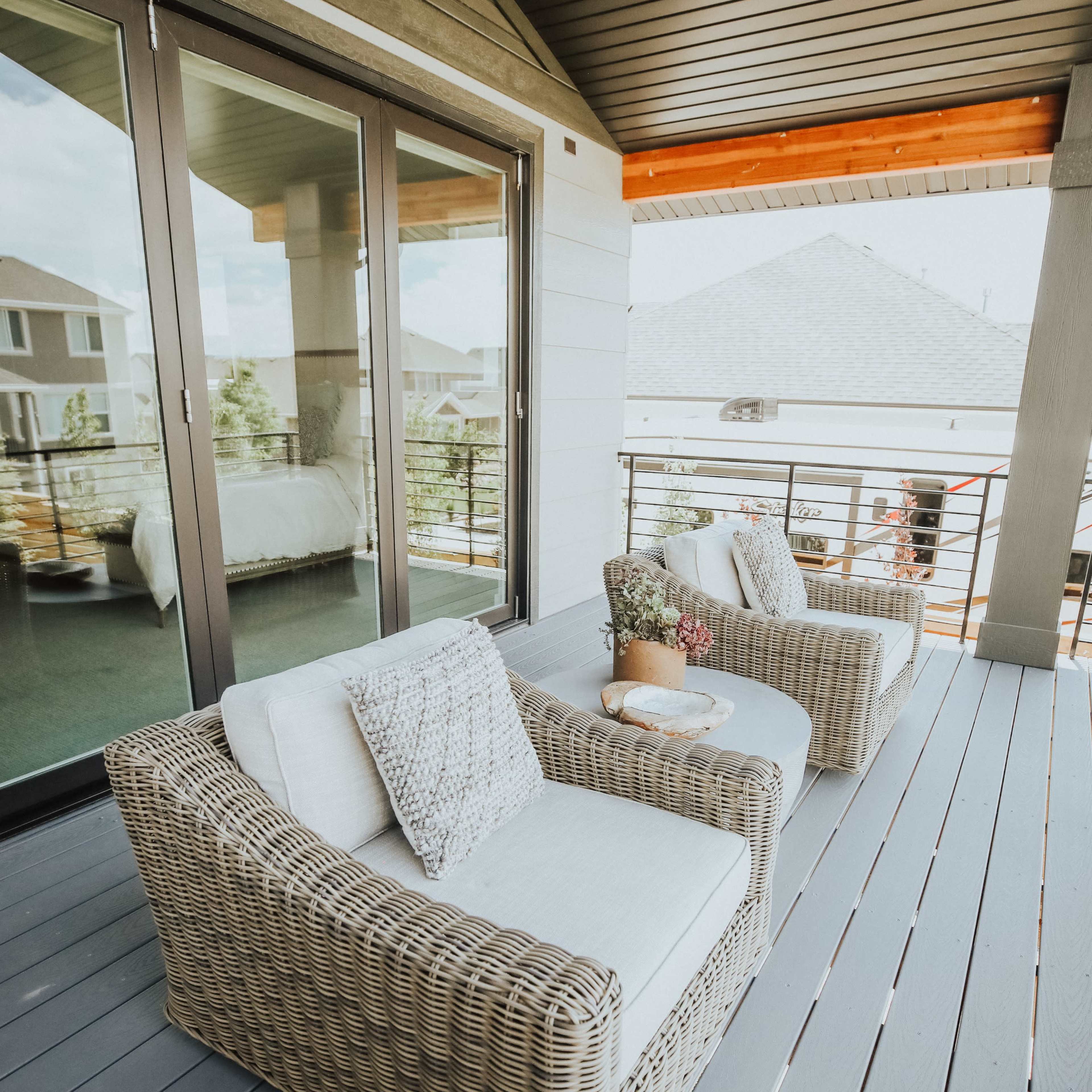 A spacious outdoor balcony with two wicker chairs and a small table.
