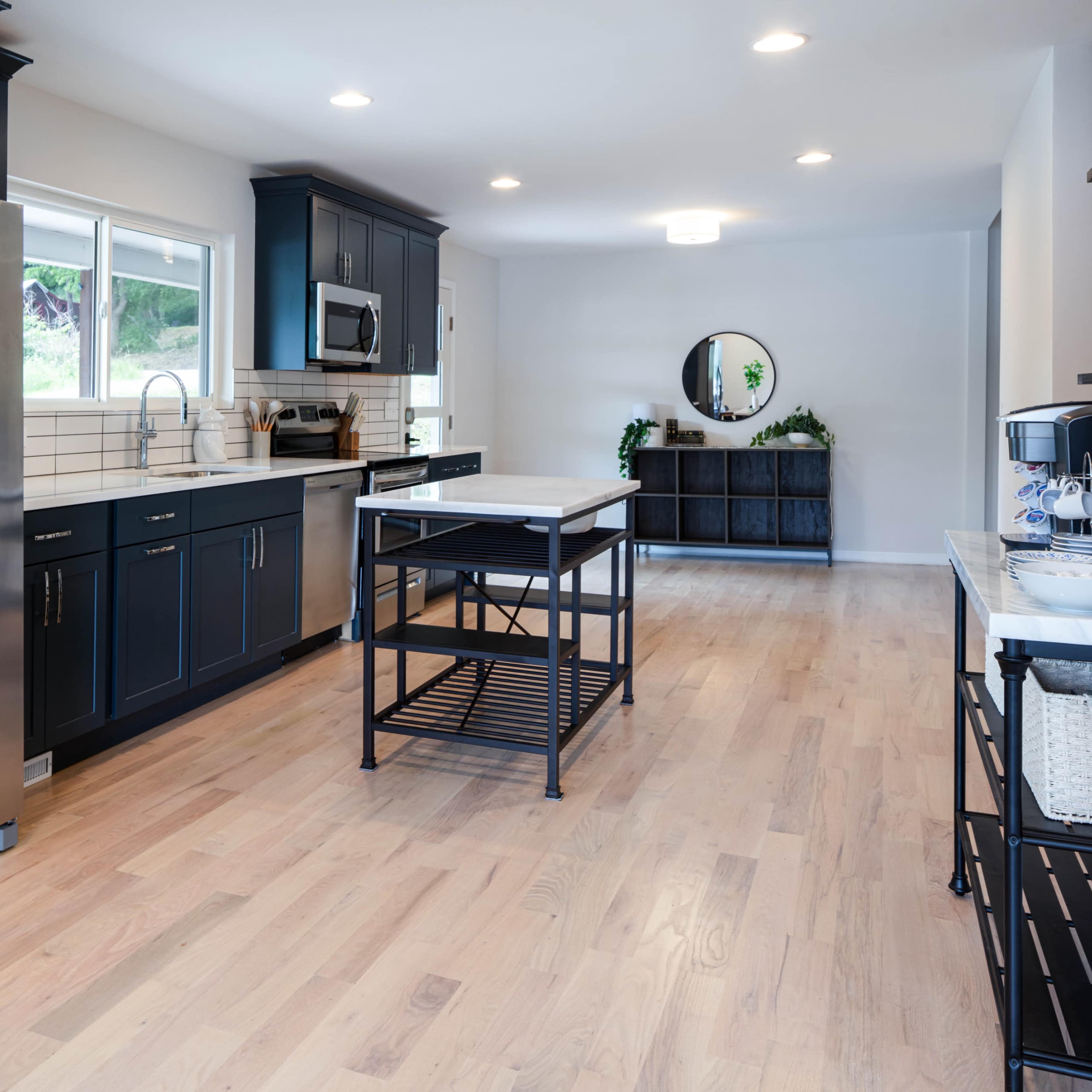 A modern kitchen featuring stainless steel appliances, dark cabinetry, and a central island with a light wood countertop.