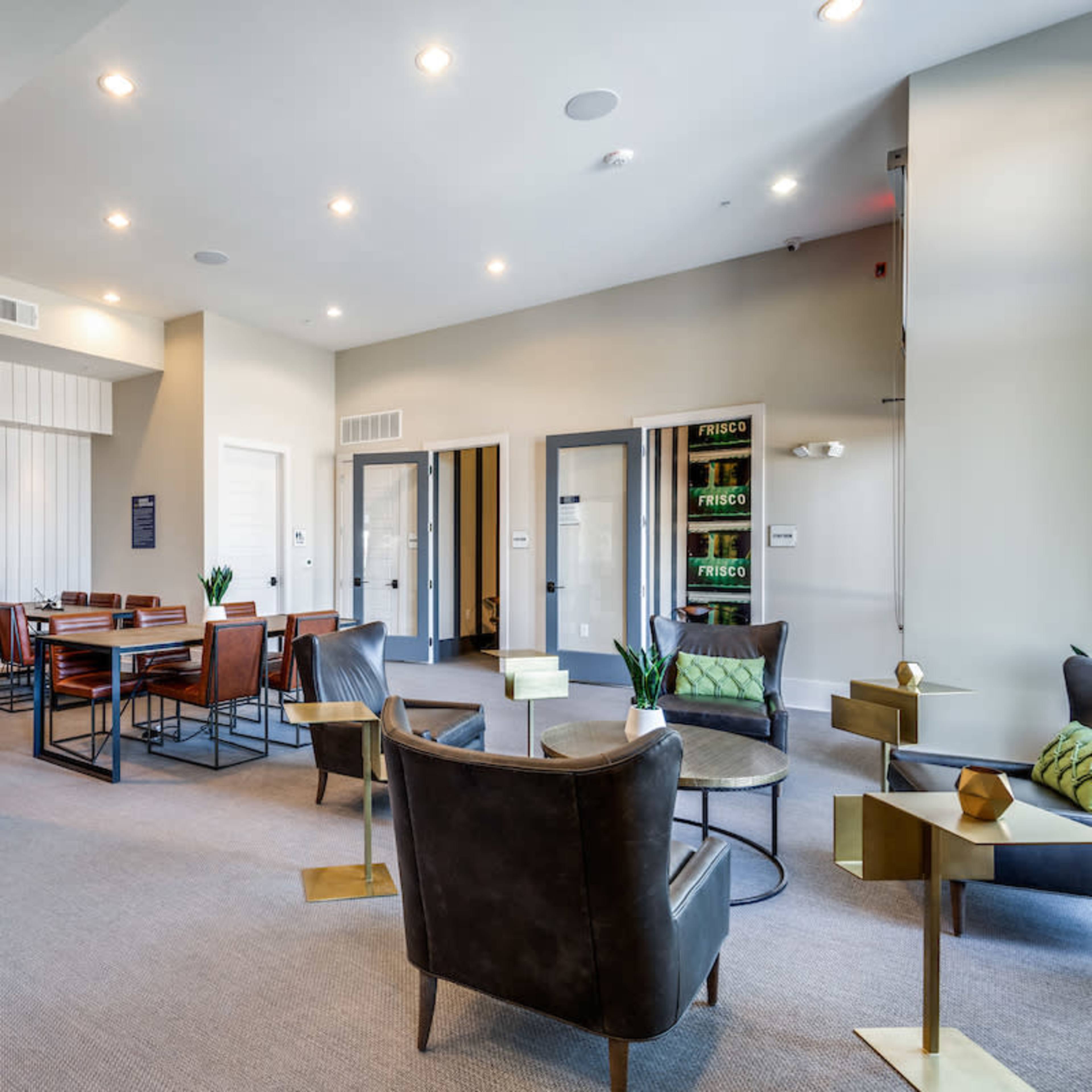A modern communal lounge area with seating, tables, and doors leading to other rooms.