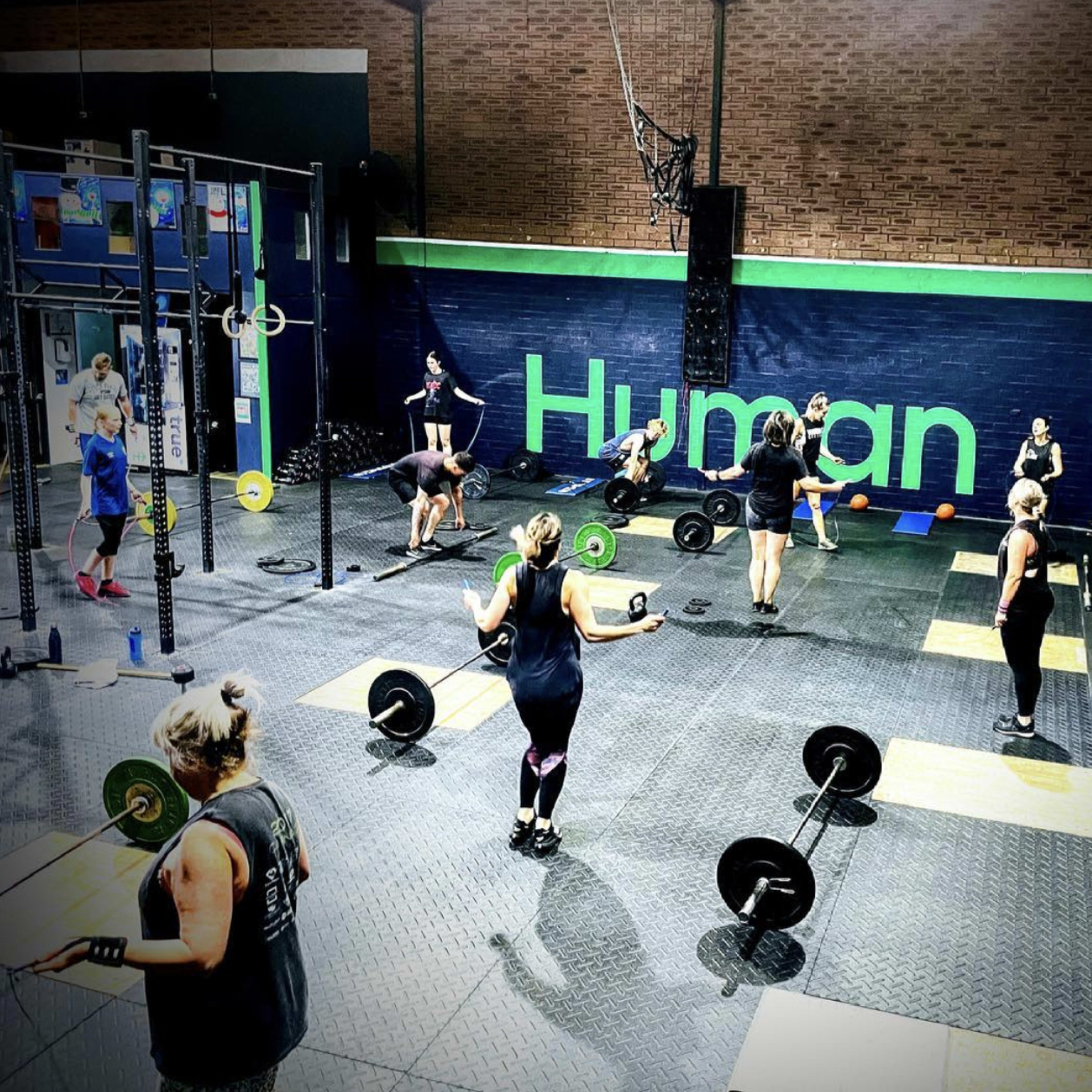 Several people are exercising with weights in a gym environment.