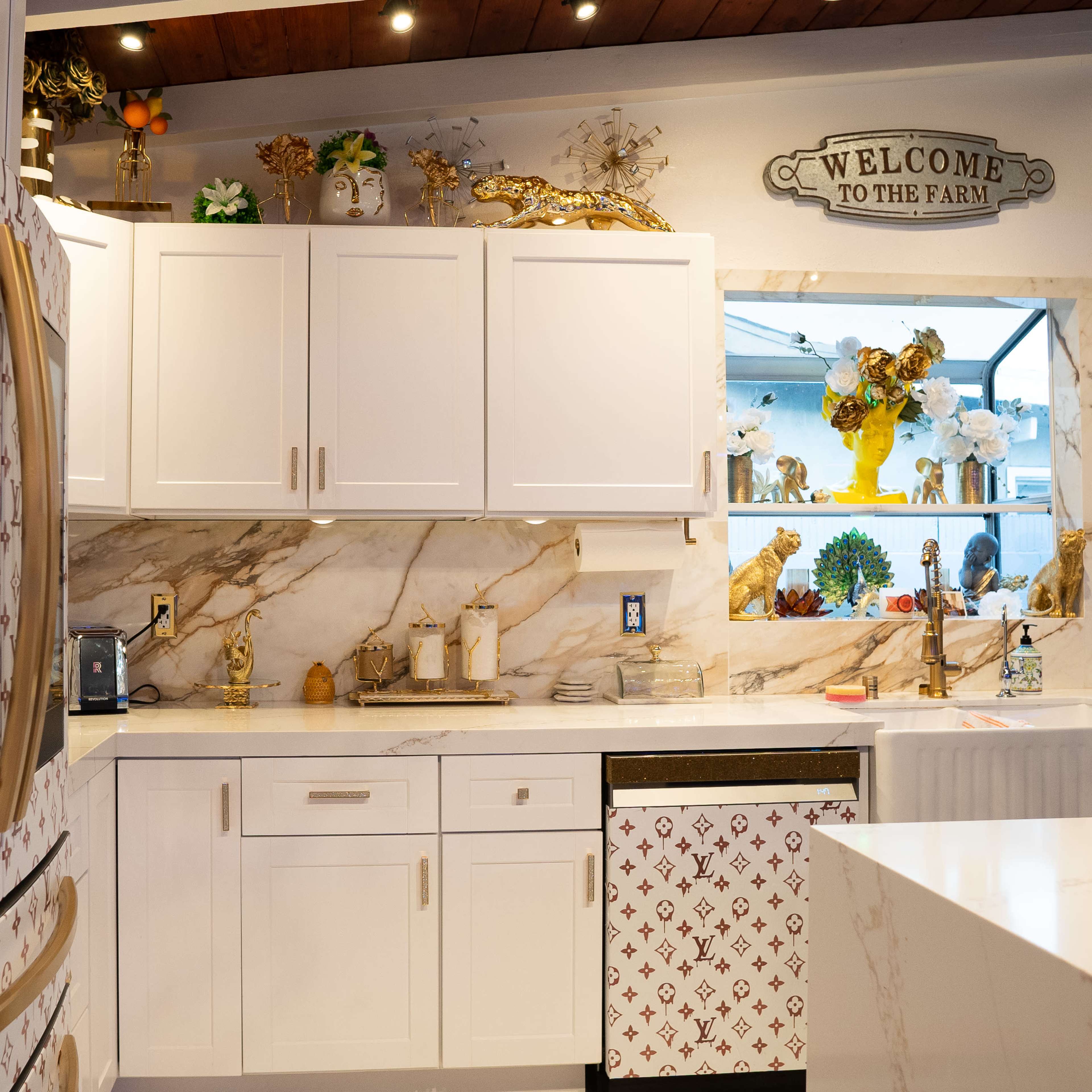 The kitchen features white cabinetry with decorative elements, a marble countertop, and a refrigerator adorned with a Louis Vuitton-inspired design.