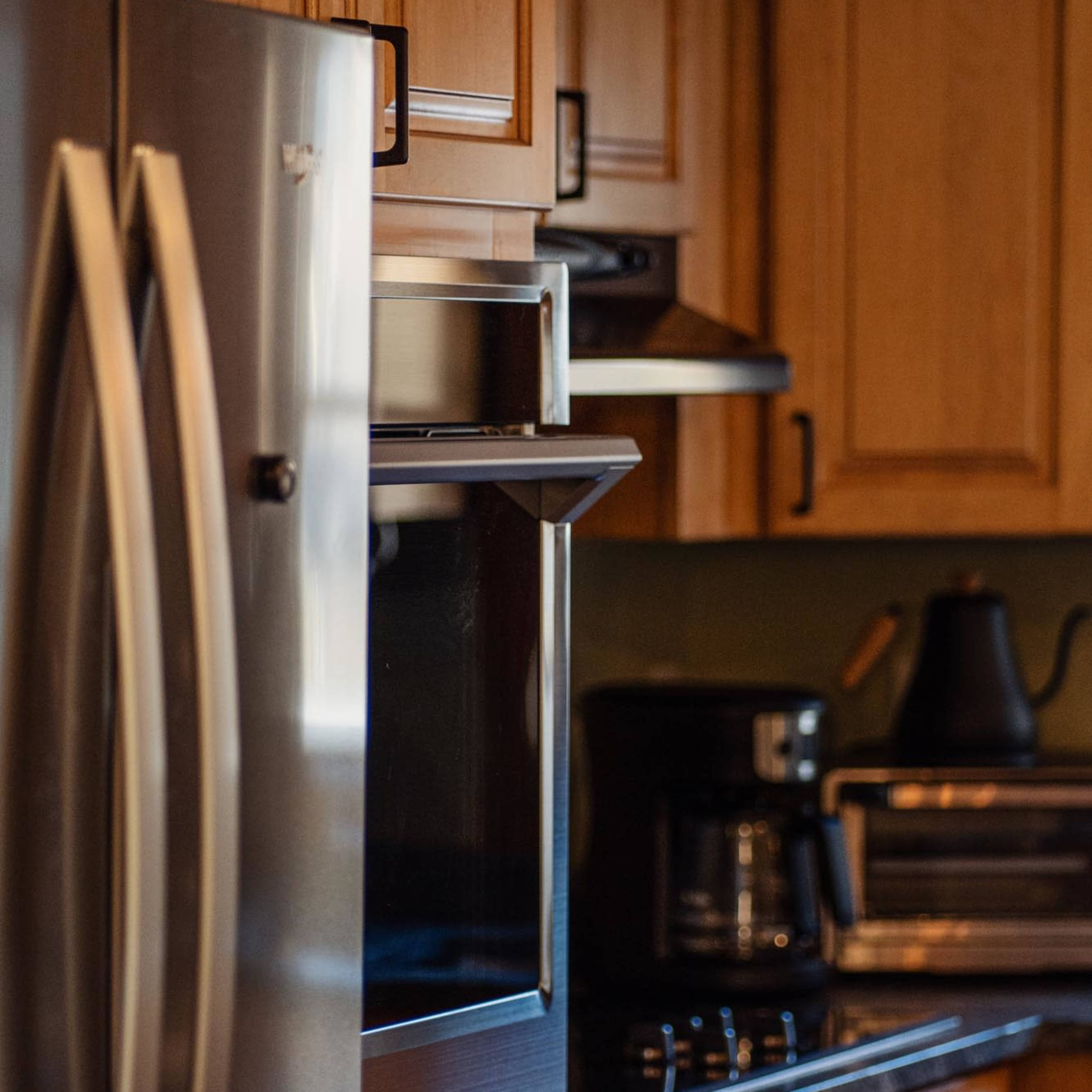 A kitchen with wooden cabinets, a stainless steel refrigerator, and various kitchen appliances, including a coffee maker and toaster.