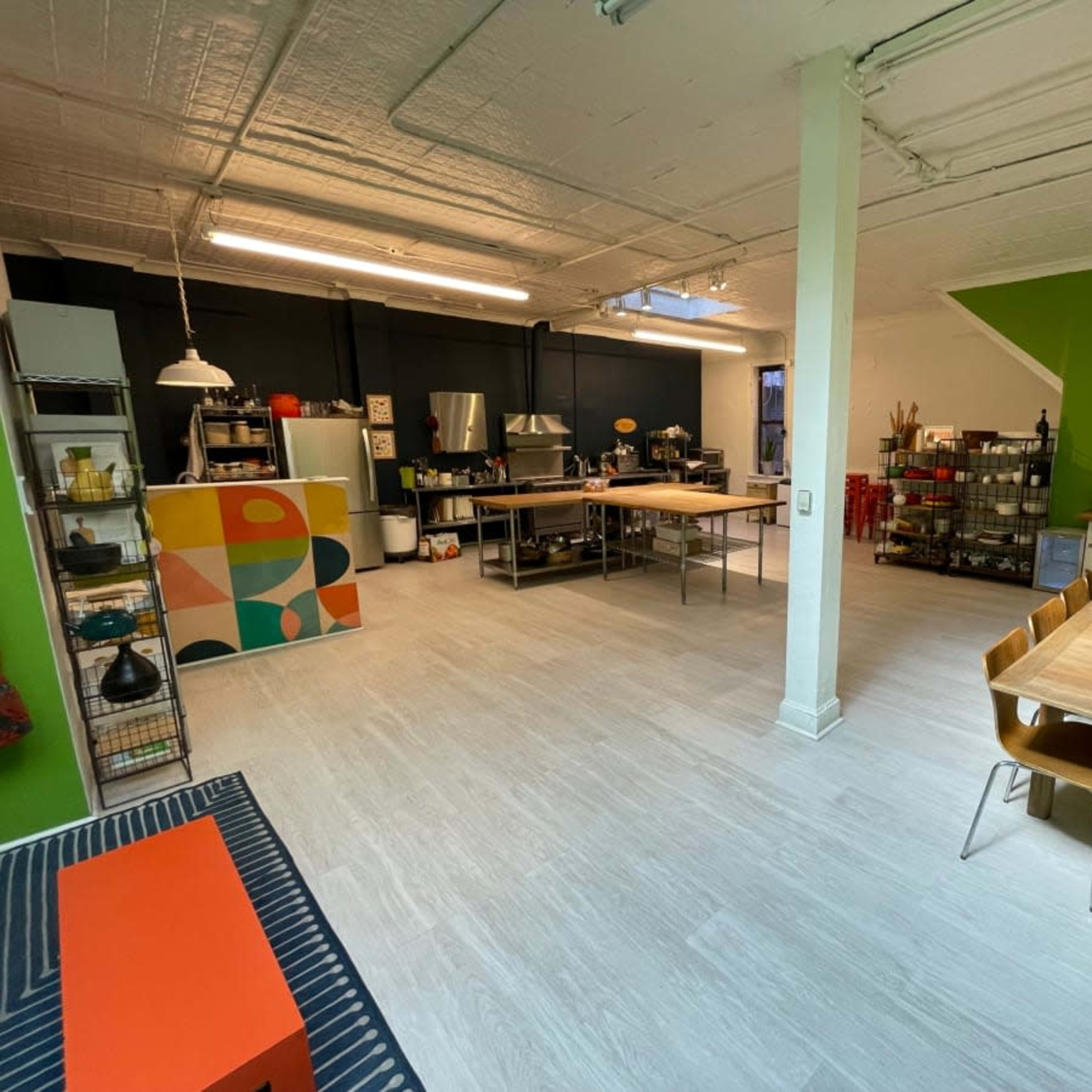 A spacious kitchen and dining area with a modern design, featuring a large table, multiple workstations, and vibrant green walls.