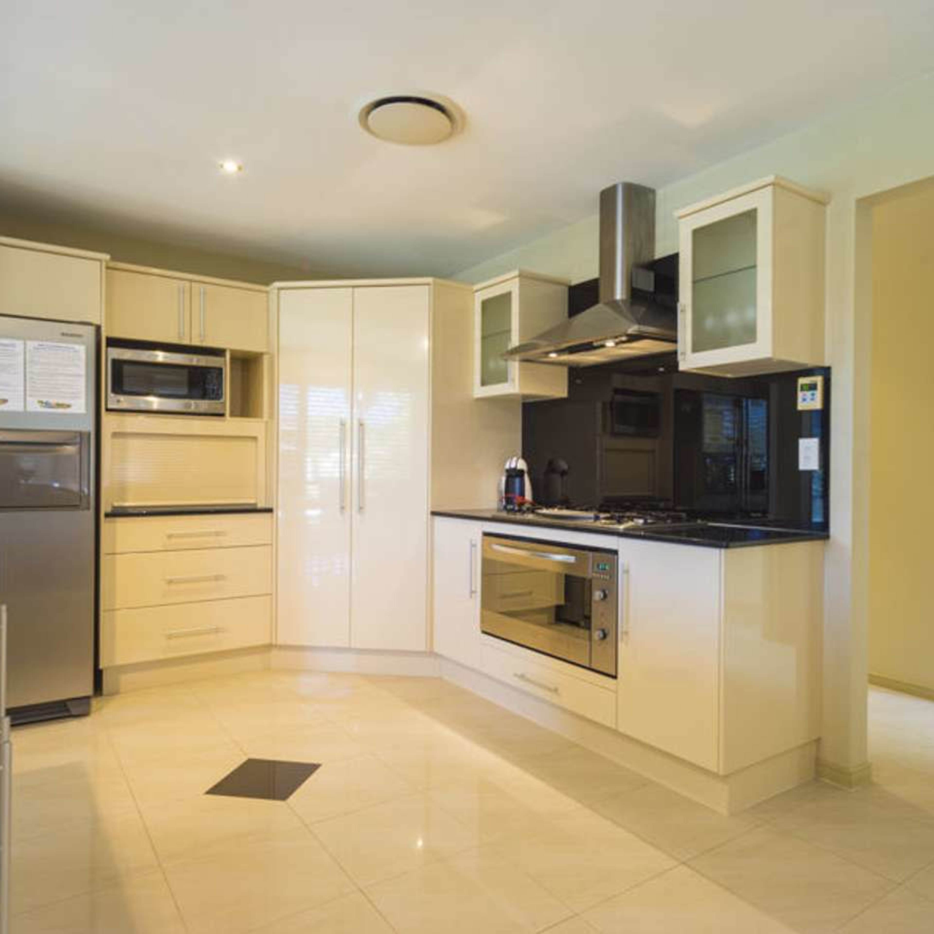 The kitchen features sleek cabinetry, stainless steel appliances, and a tiled floor.