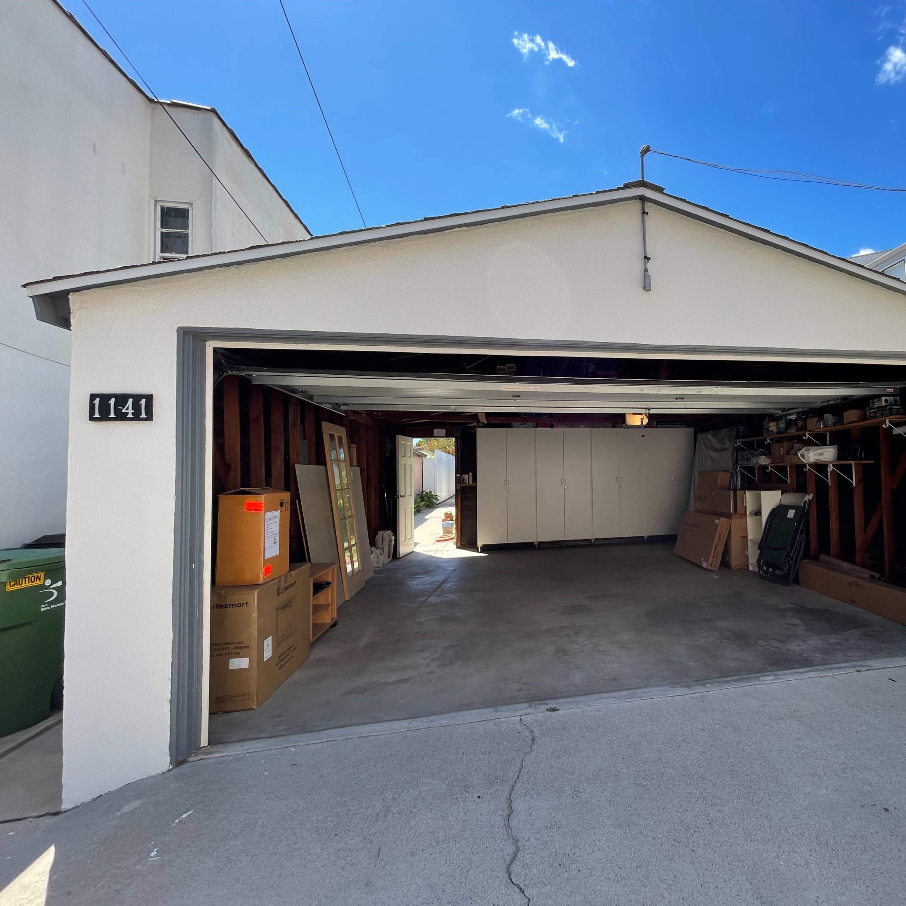 An open garage with a concrete floor and cardboard boxes inside, located at 1141.