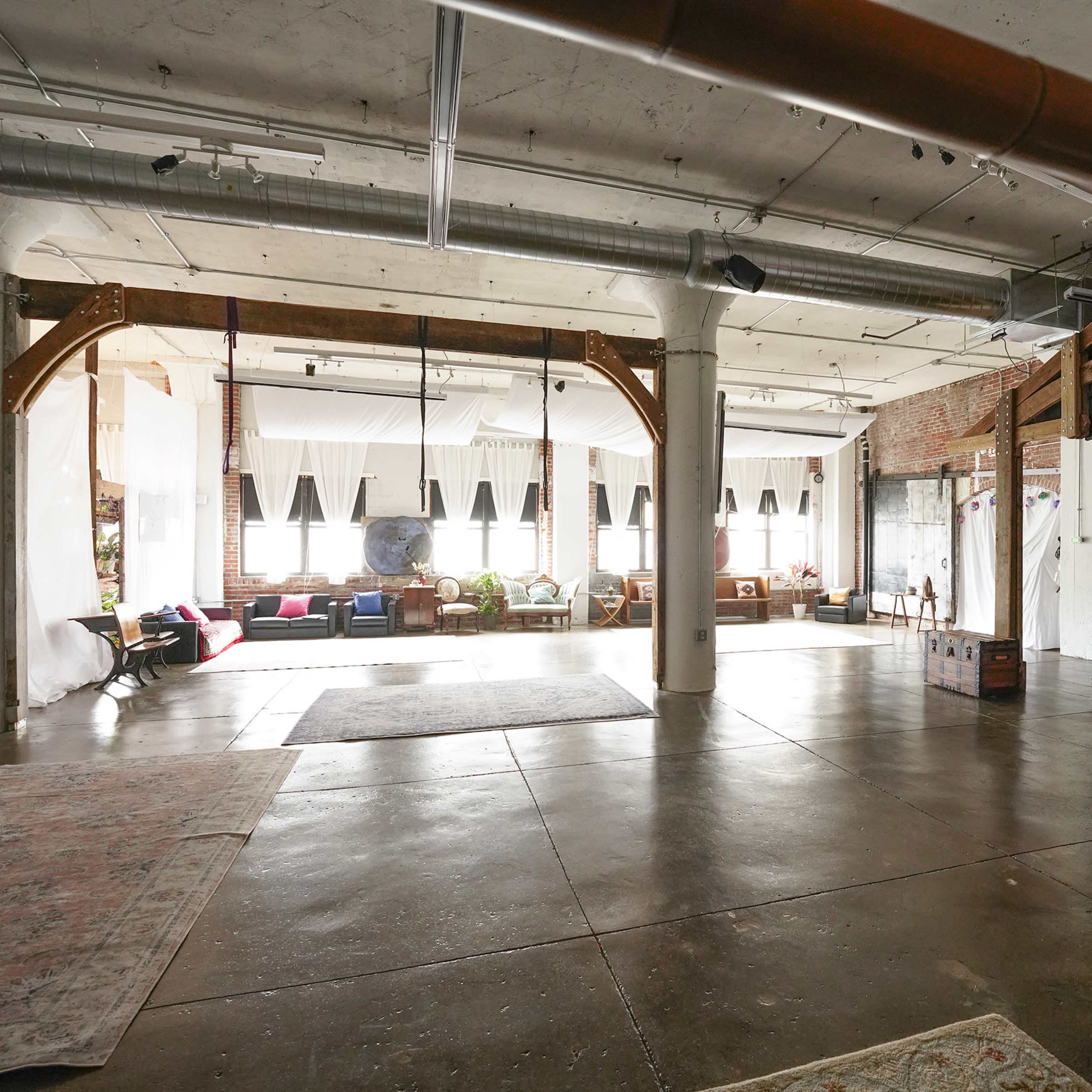 The spacious interior features exposed beams, large windows, and a variety of seating areas with decorative elements.