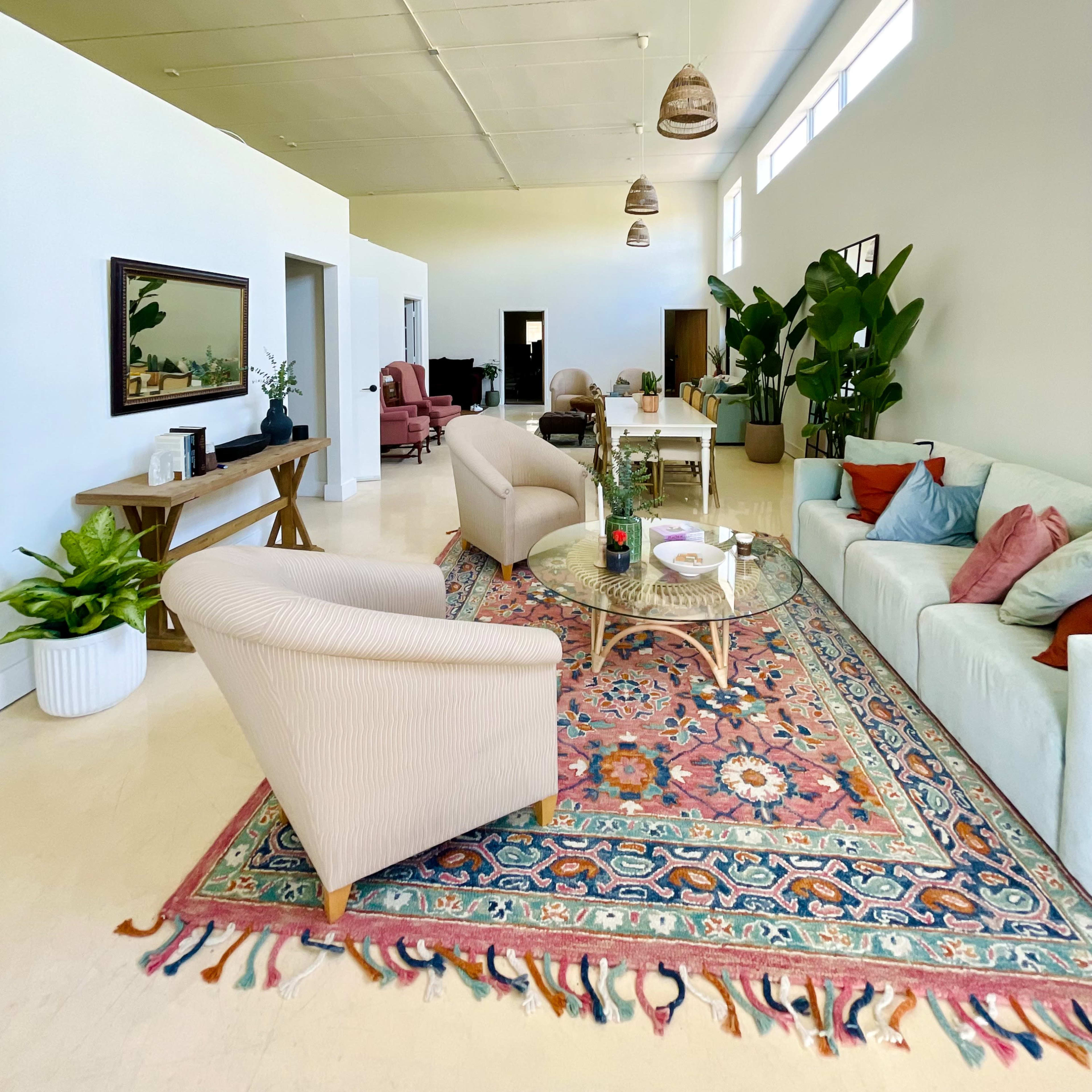 A spacious, well-lit living area with a mix of seating options, a coffee table, and decorative plants.