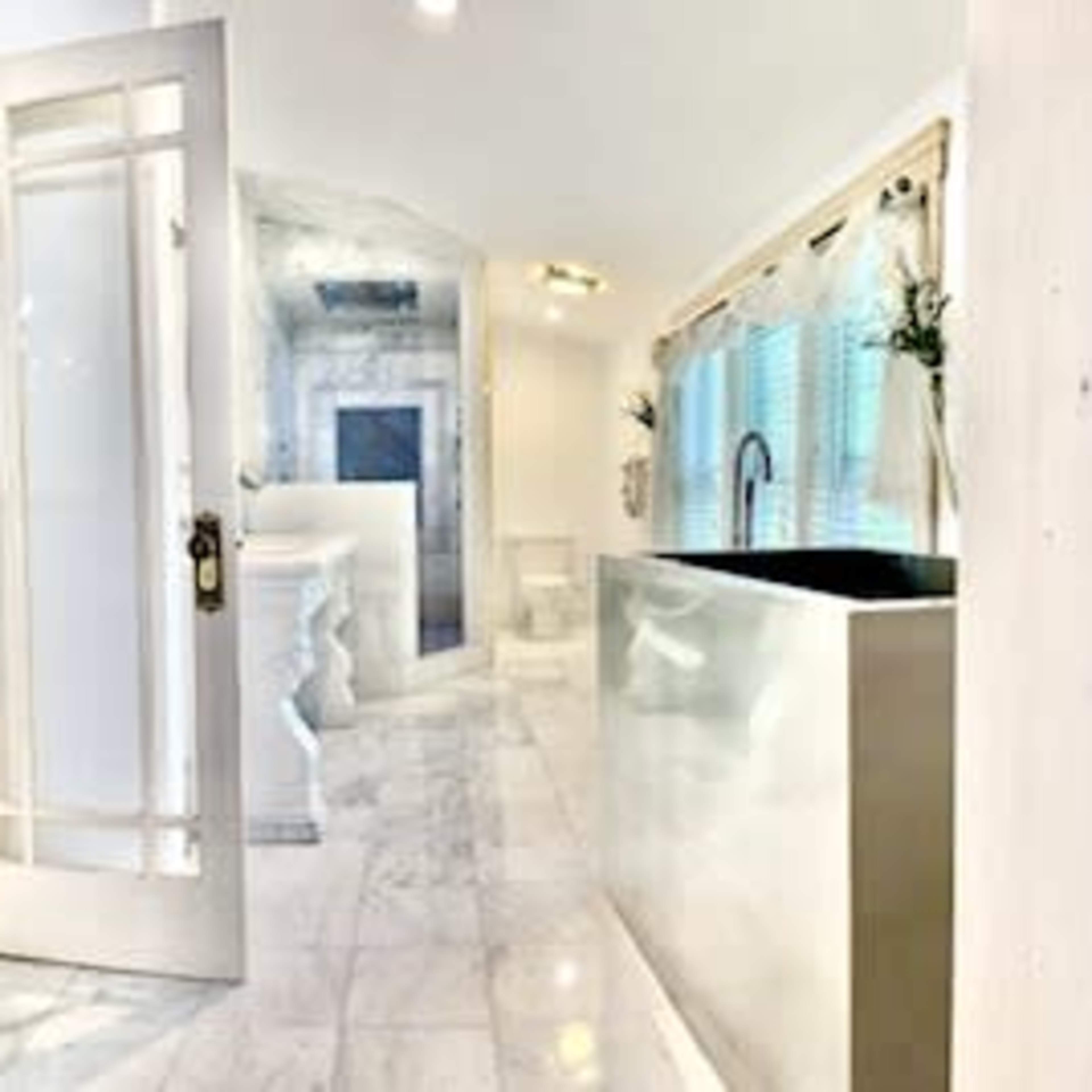 A modern bathroom with marble flooring, a sleek sink, and a door leading to another room.