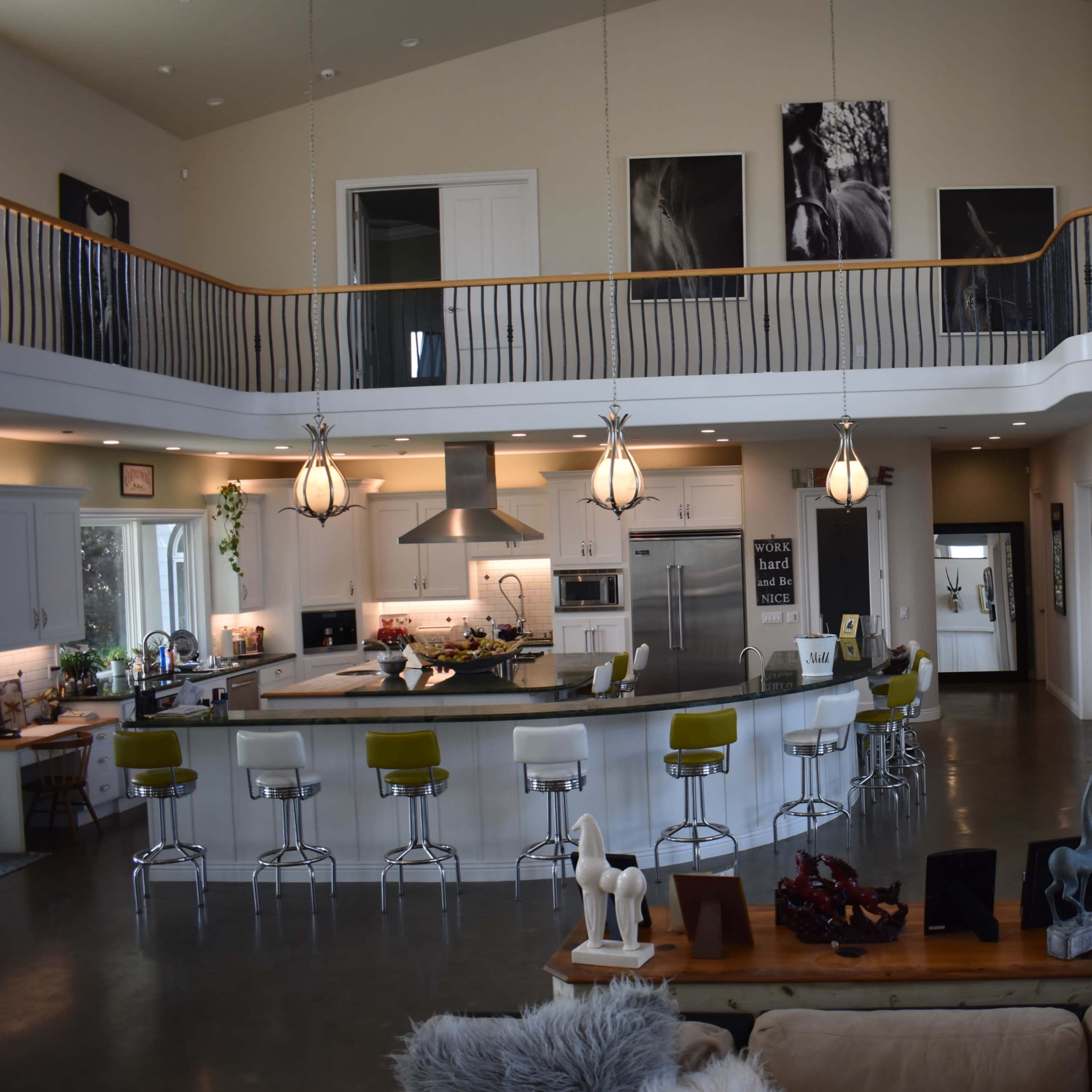 A spacious, modern living area with a kitchen island, seating area, and a balcony overlooking the space.