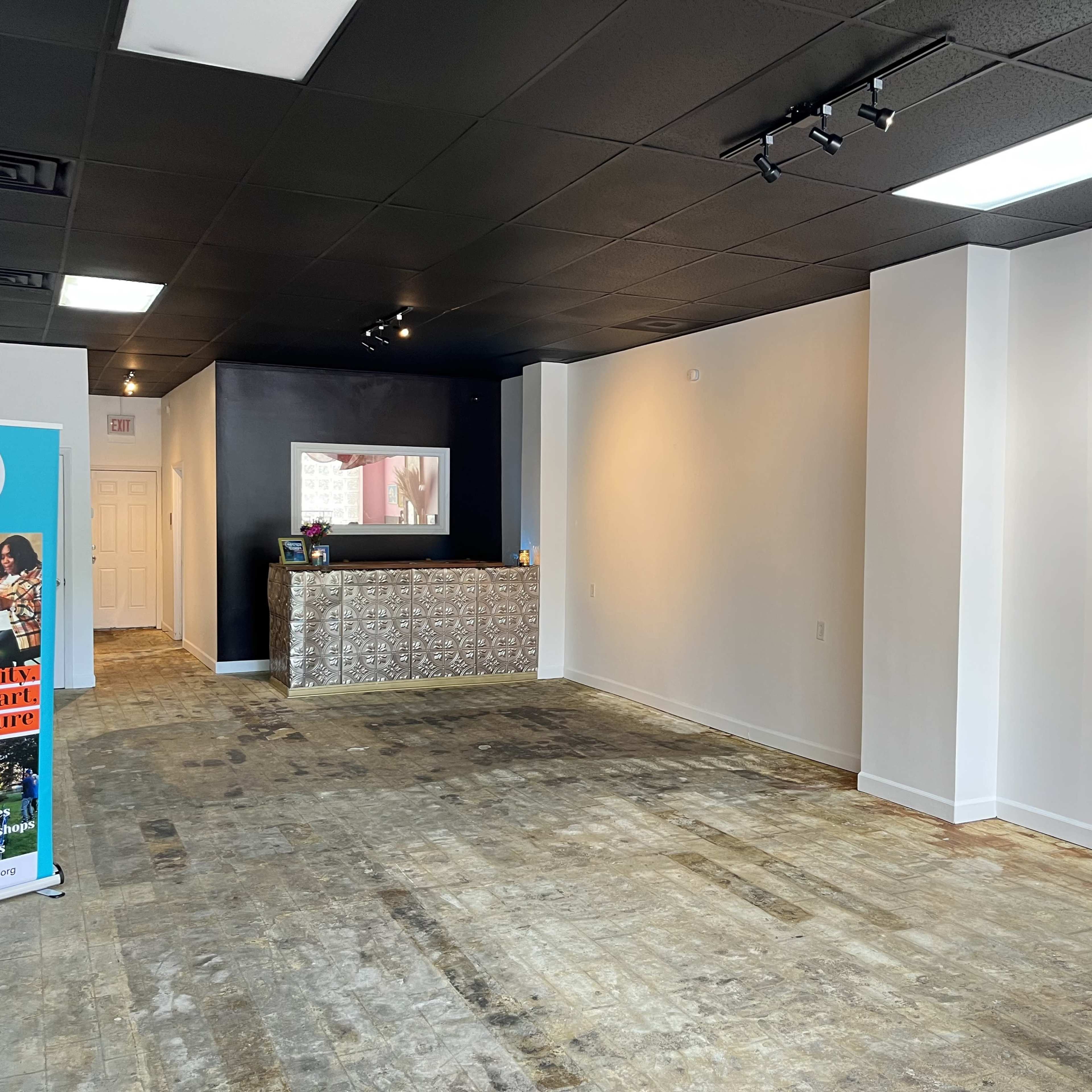 An empty interior space featuring a reception area with a patterned counter and bare wooden floors.