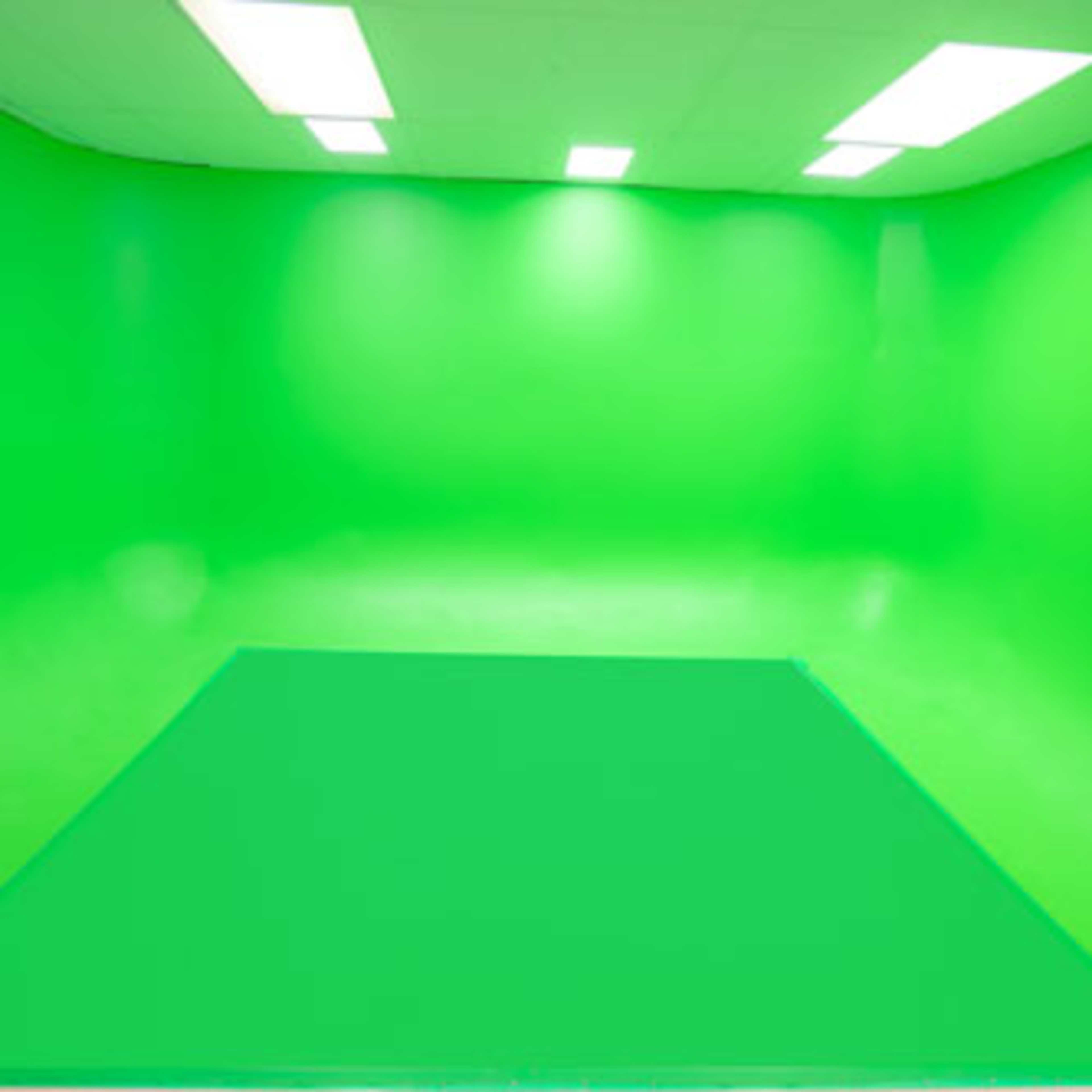 An empty green screen studio with a seamless green backdrop and overhead lighting.