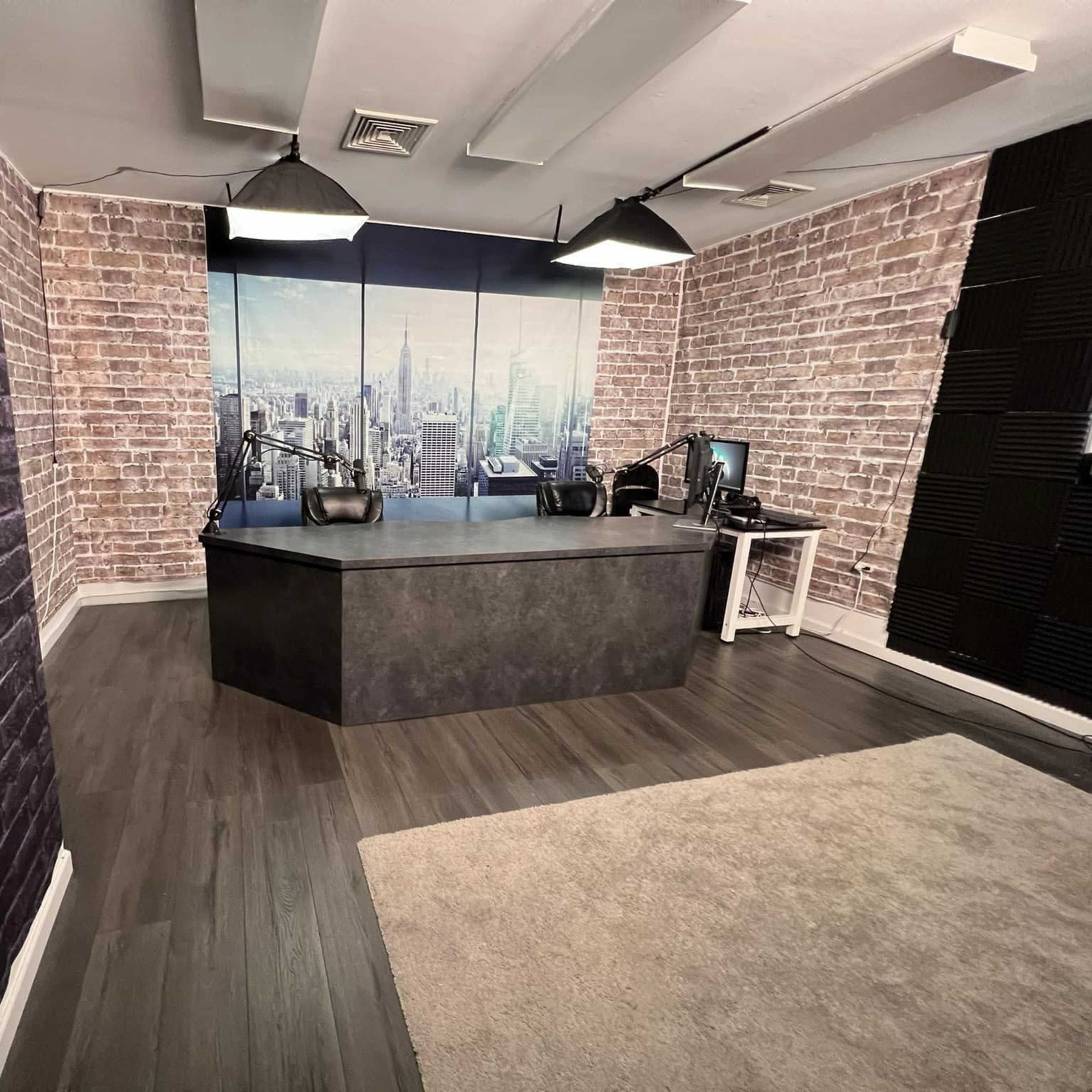 A modern office space with exposed brick walls, a large desk, and a backdrop of a city skyline.