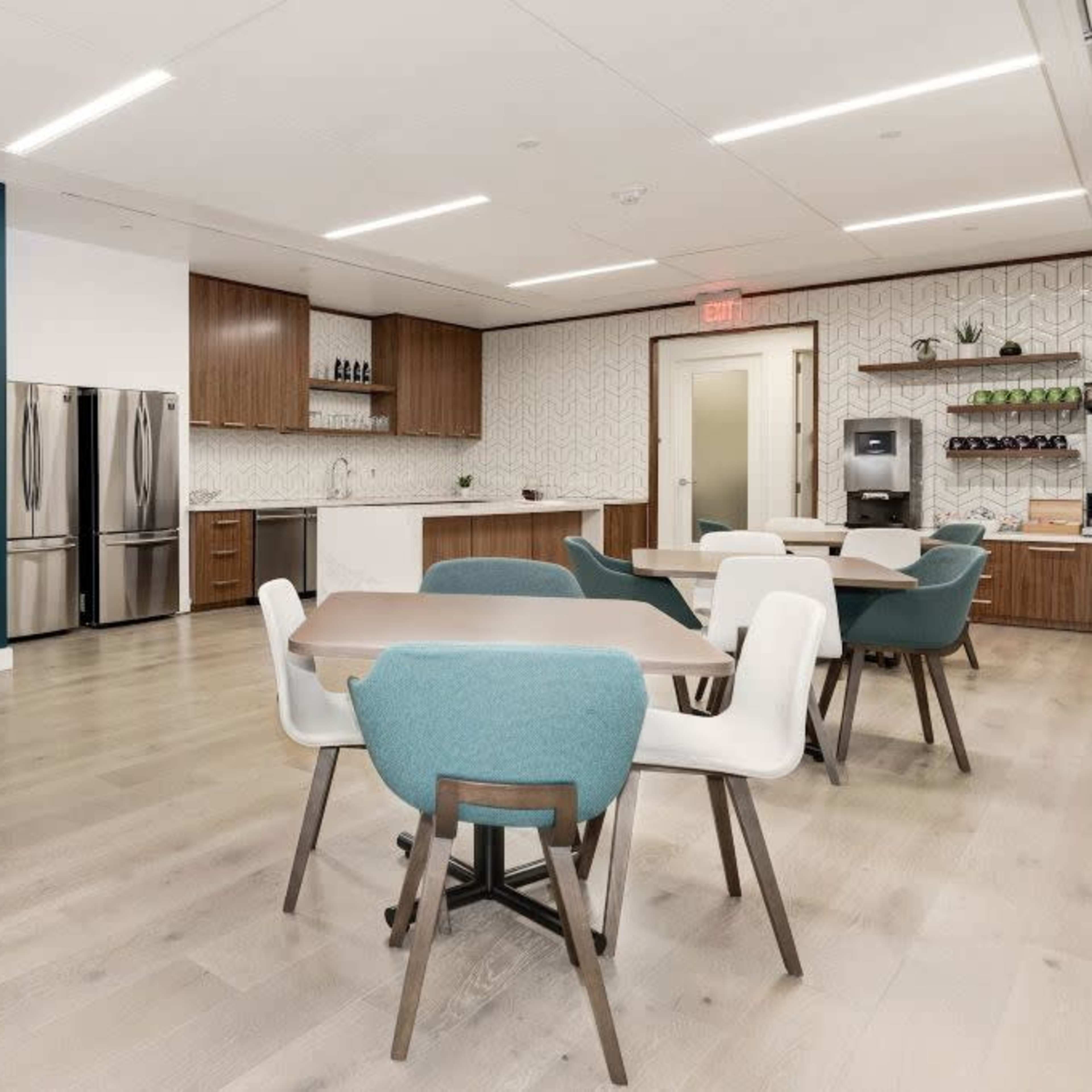 A modern kitchen and dining area with a table and chairs, featuring stainless steel appliances and a mural on the wall.