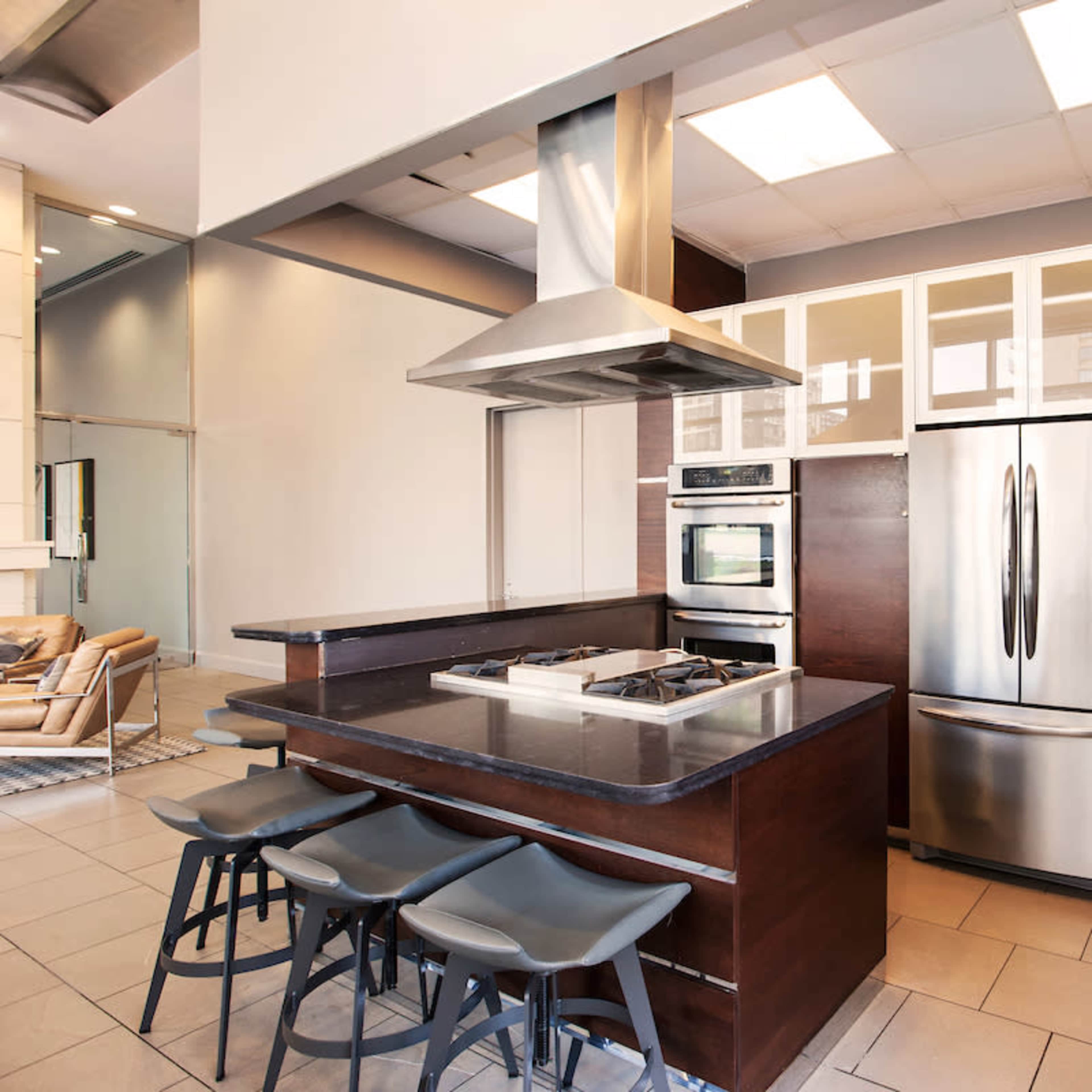 A modern kitchen featuring stainless steel appliances, a central island with seating, and wooden cabinetry.