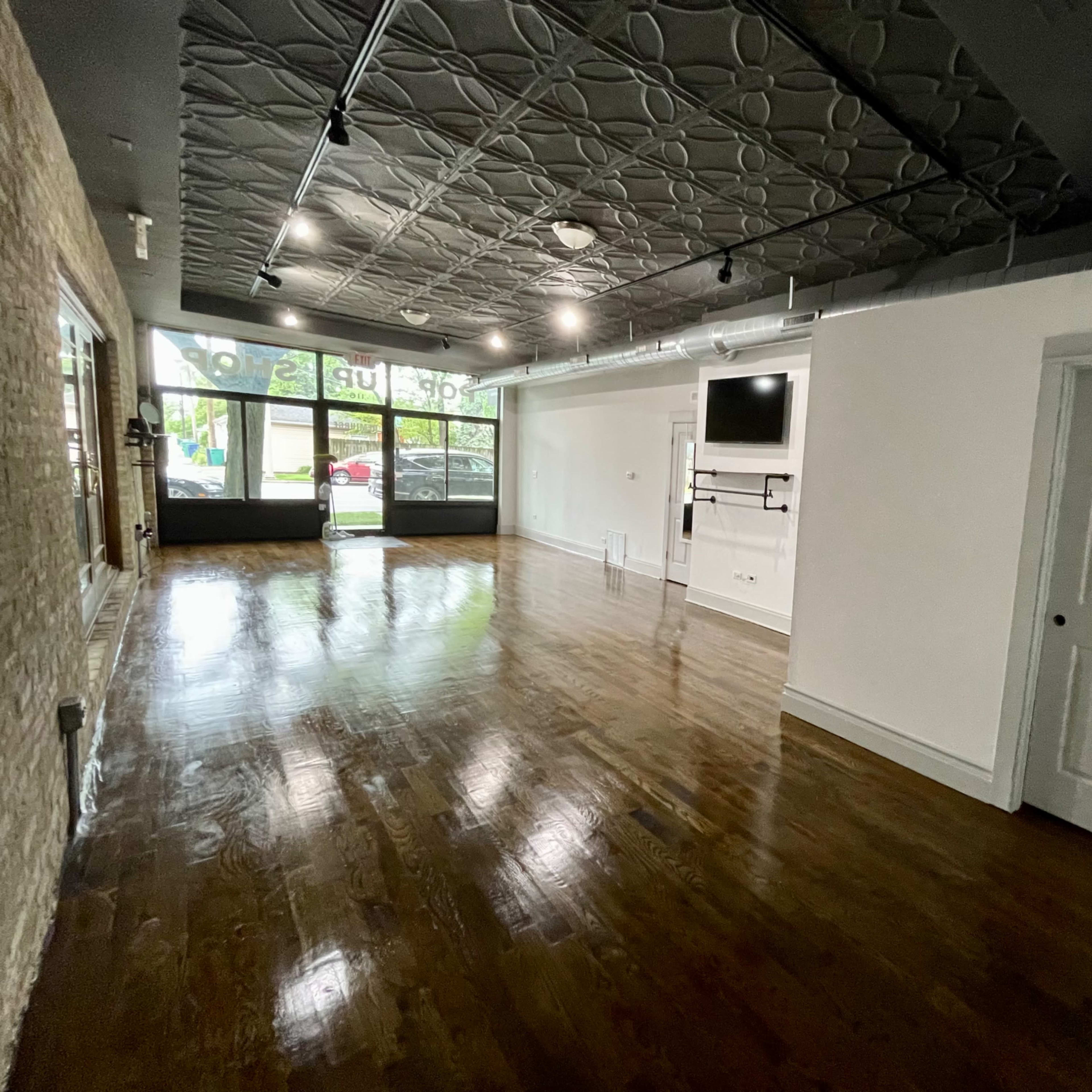 An empty room with hardwood floors, a textured ceiling, a wall-mounted screen, and a door on the right side.