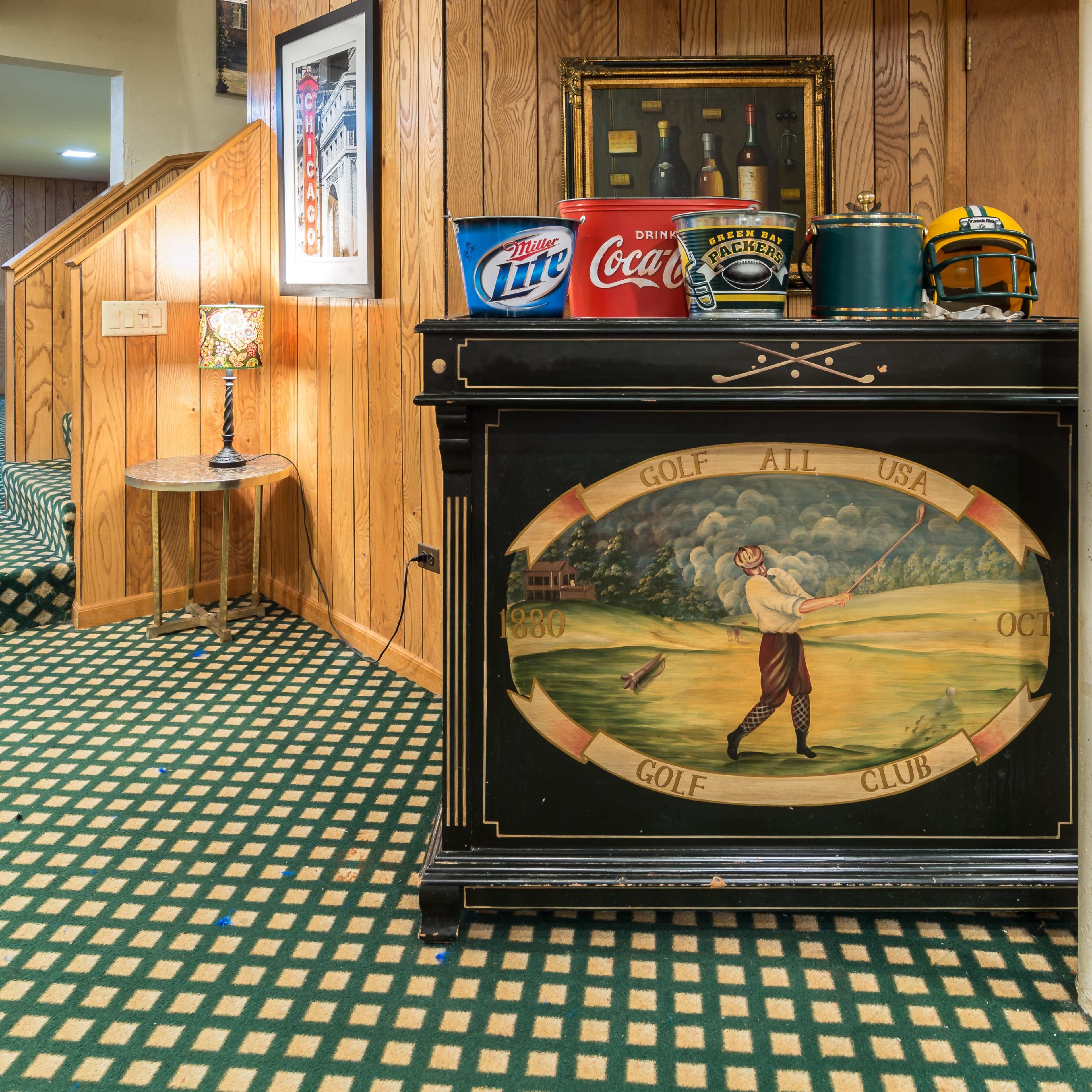 A basement area featuring a wooden bar with golf-themed decor, vintage bottles, and a checkered floor.