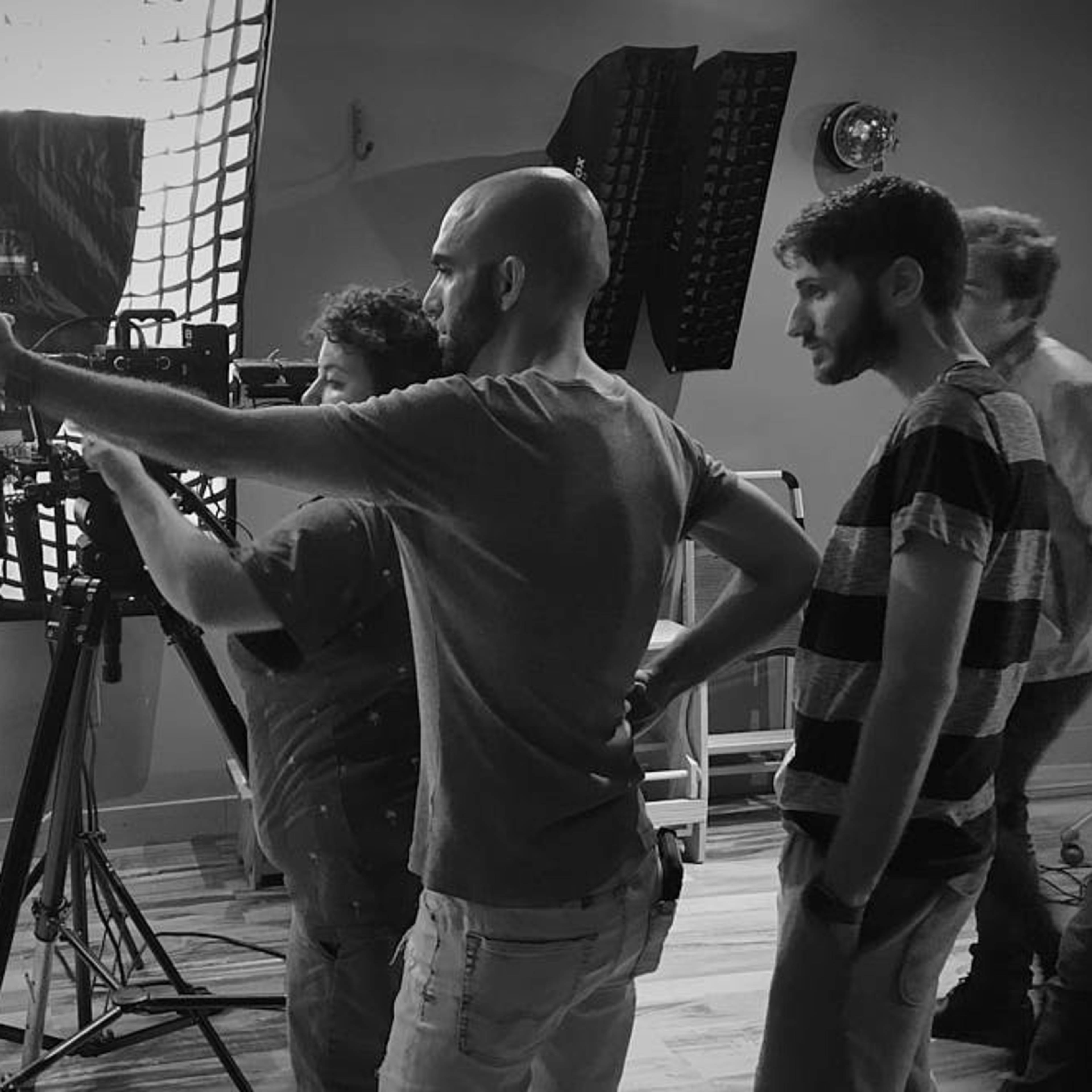 A group of three people operates a camera setup in a studio space.