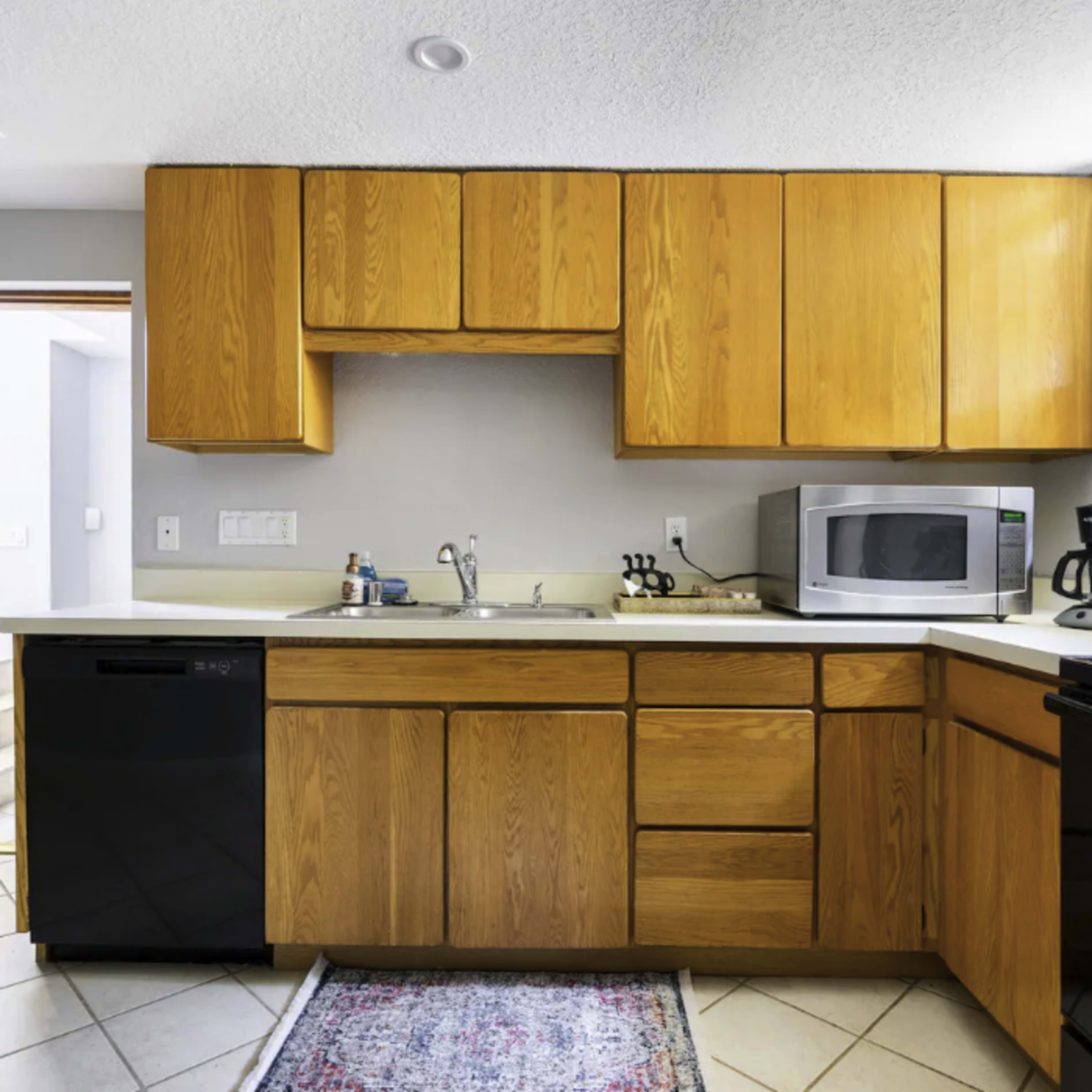 A compact kitchen with wooden cabinets, a sink, a microwave, and an electric stove.