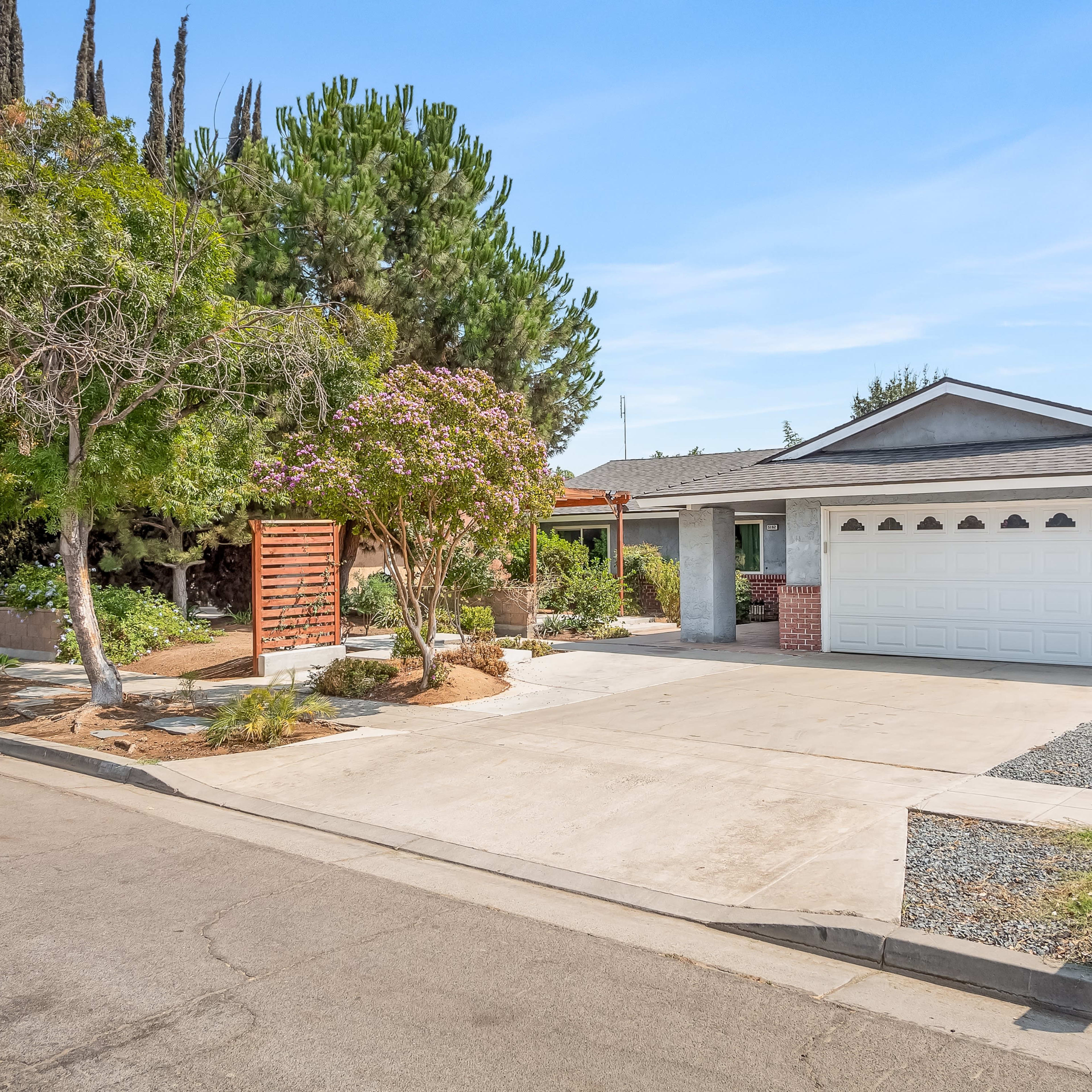 A suburban house with a gray exterior, a two-car garage, and landscaped front yard along a quiet street.