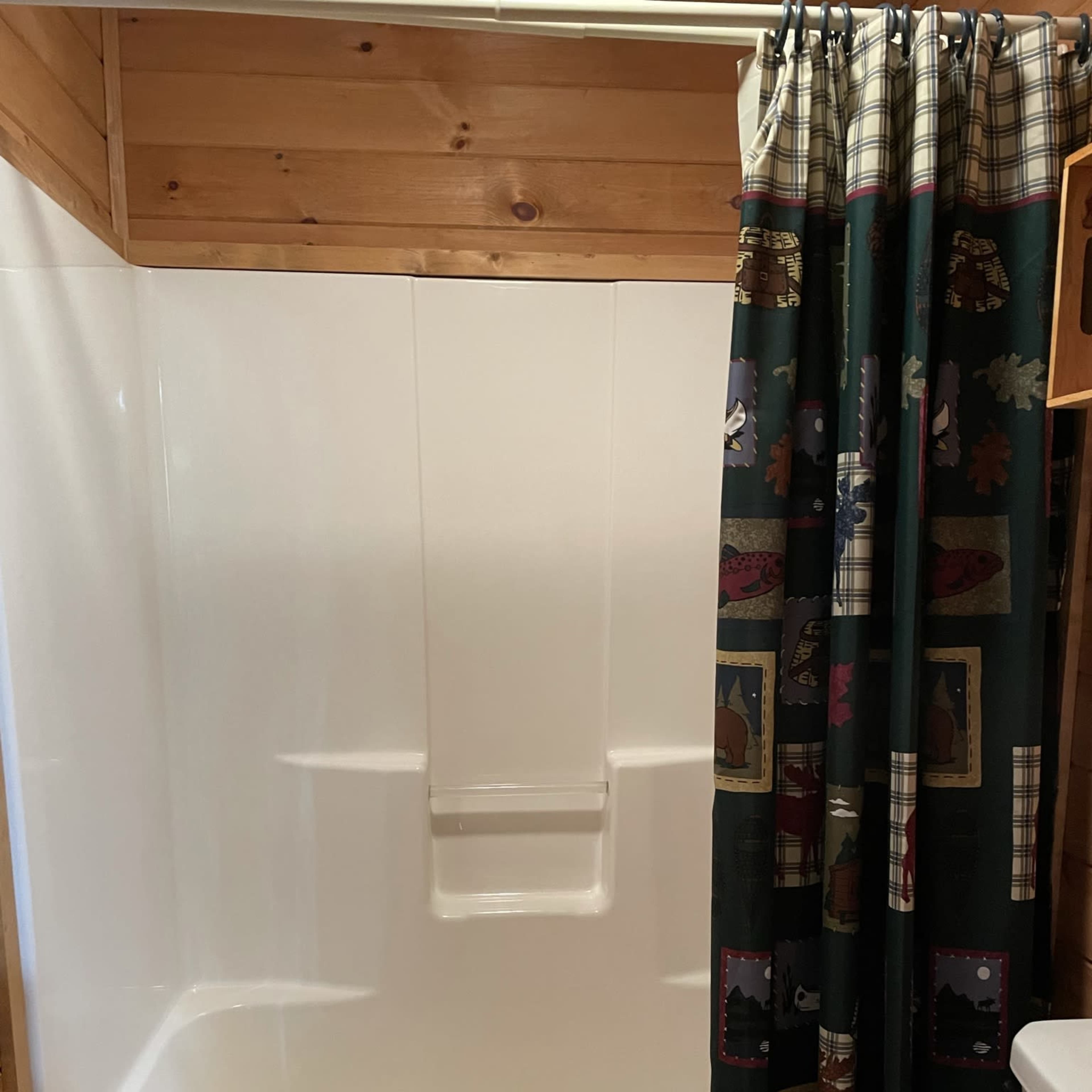 A bathroom with a white bathtub and shower combination, a patterned shower curtain, and a toilet.