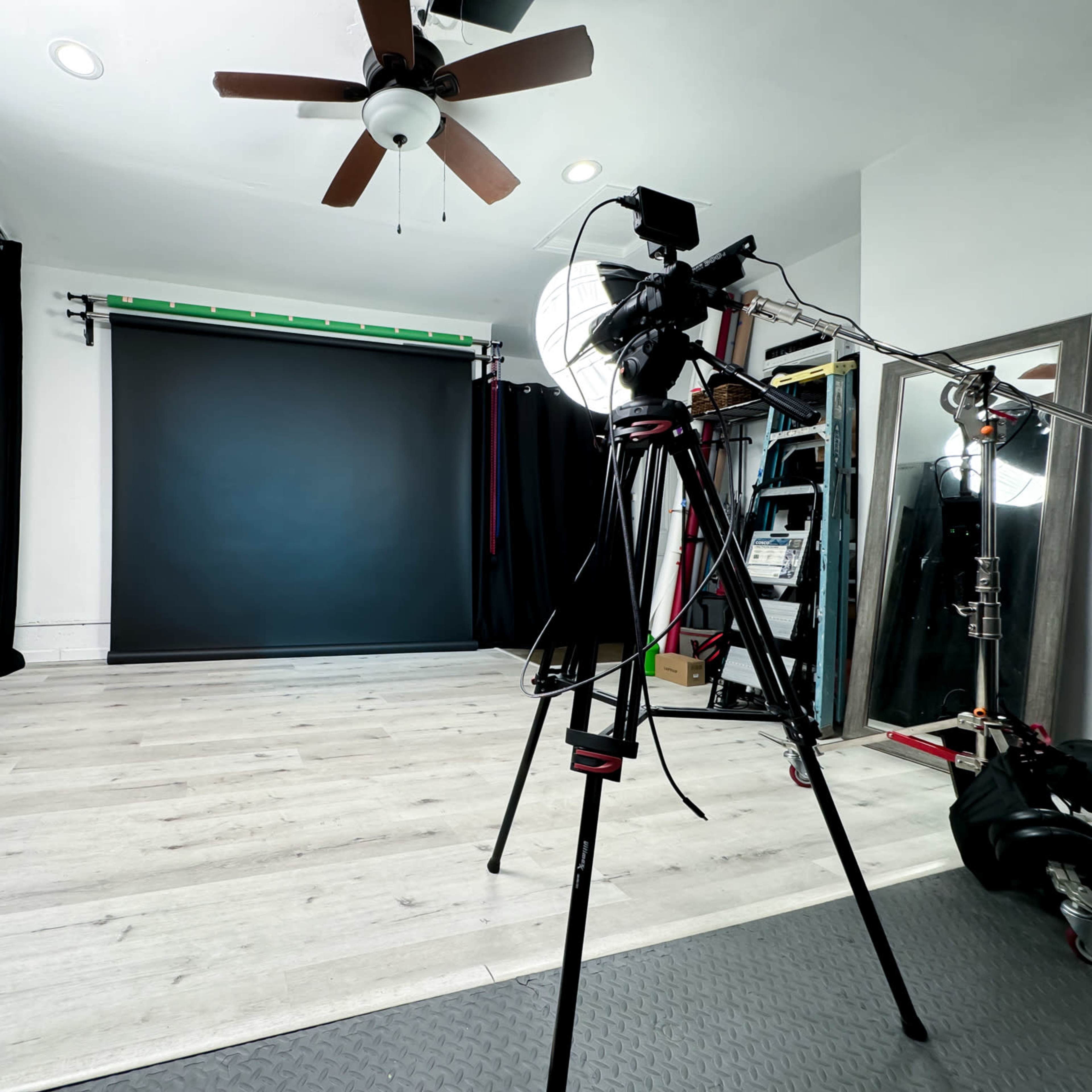 A photography studio equipped with a backdrop, lighting equipment, and a camera set on a tripod.