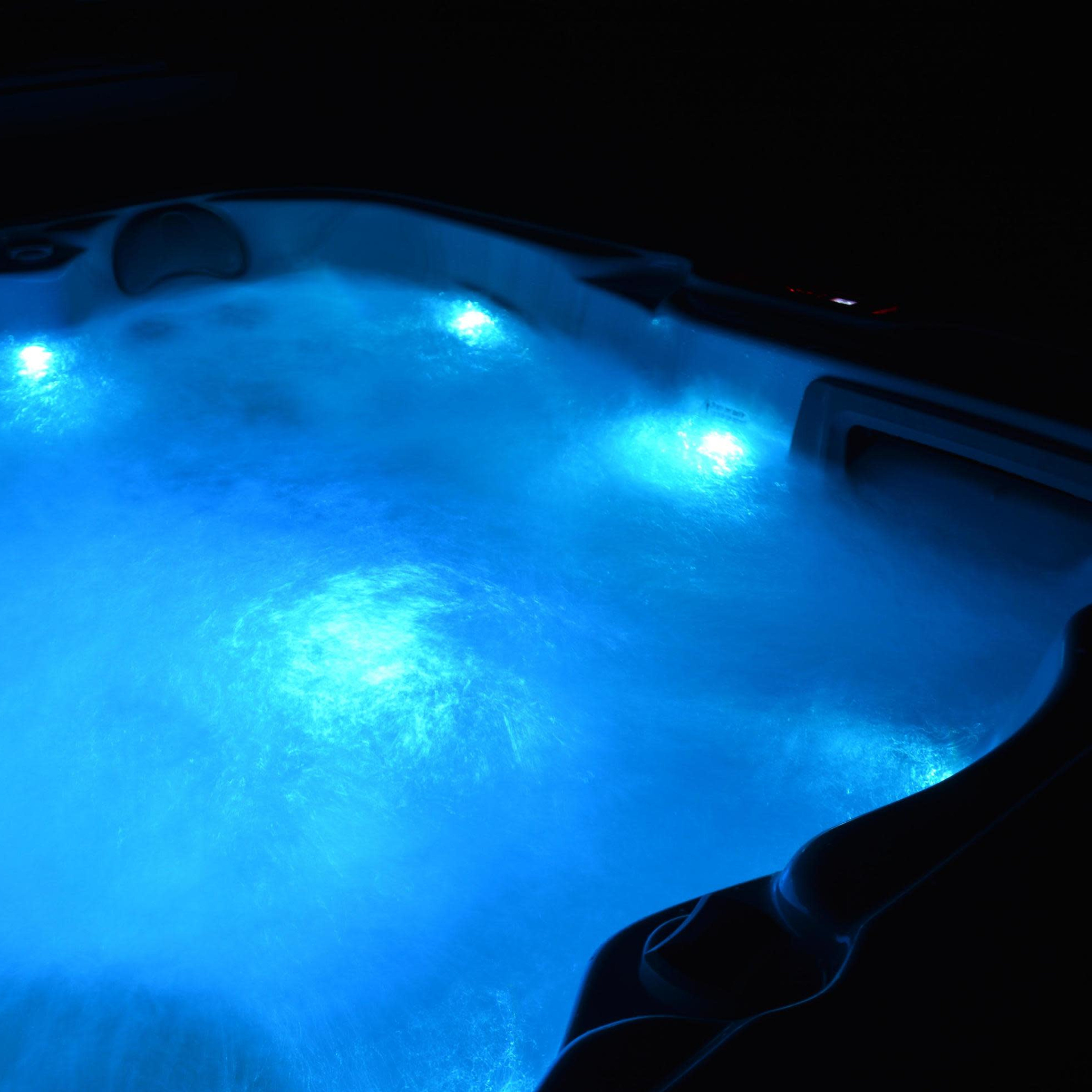 A hot tub with swirling water illuminated by blue lights in a dark setting.