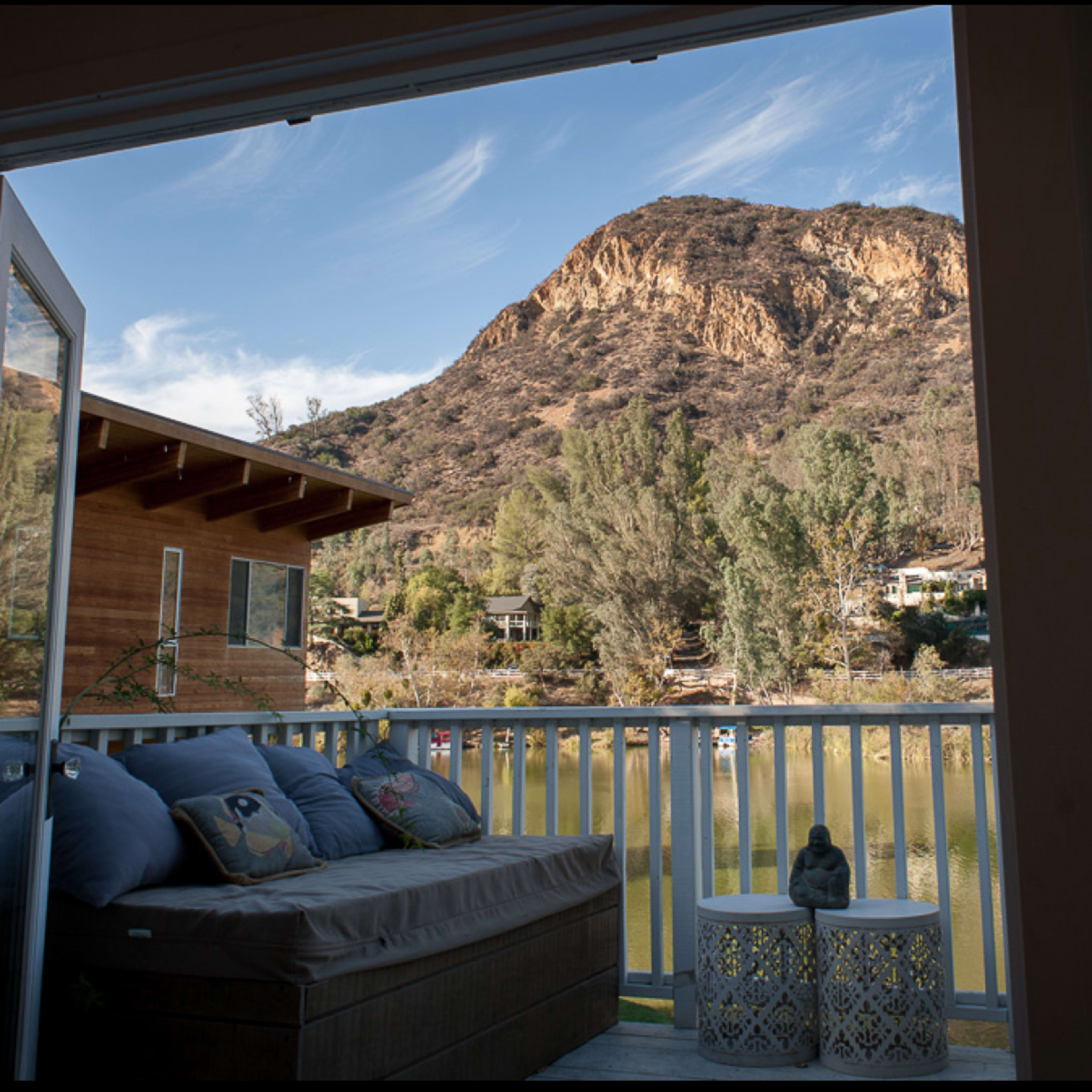 An open door view of a balcony overlooking a lake and a mountainous landscape.