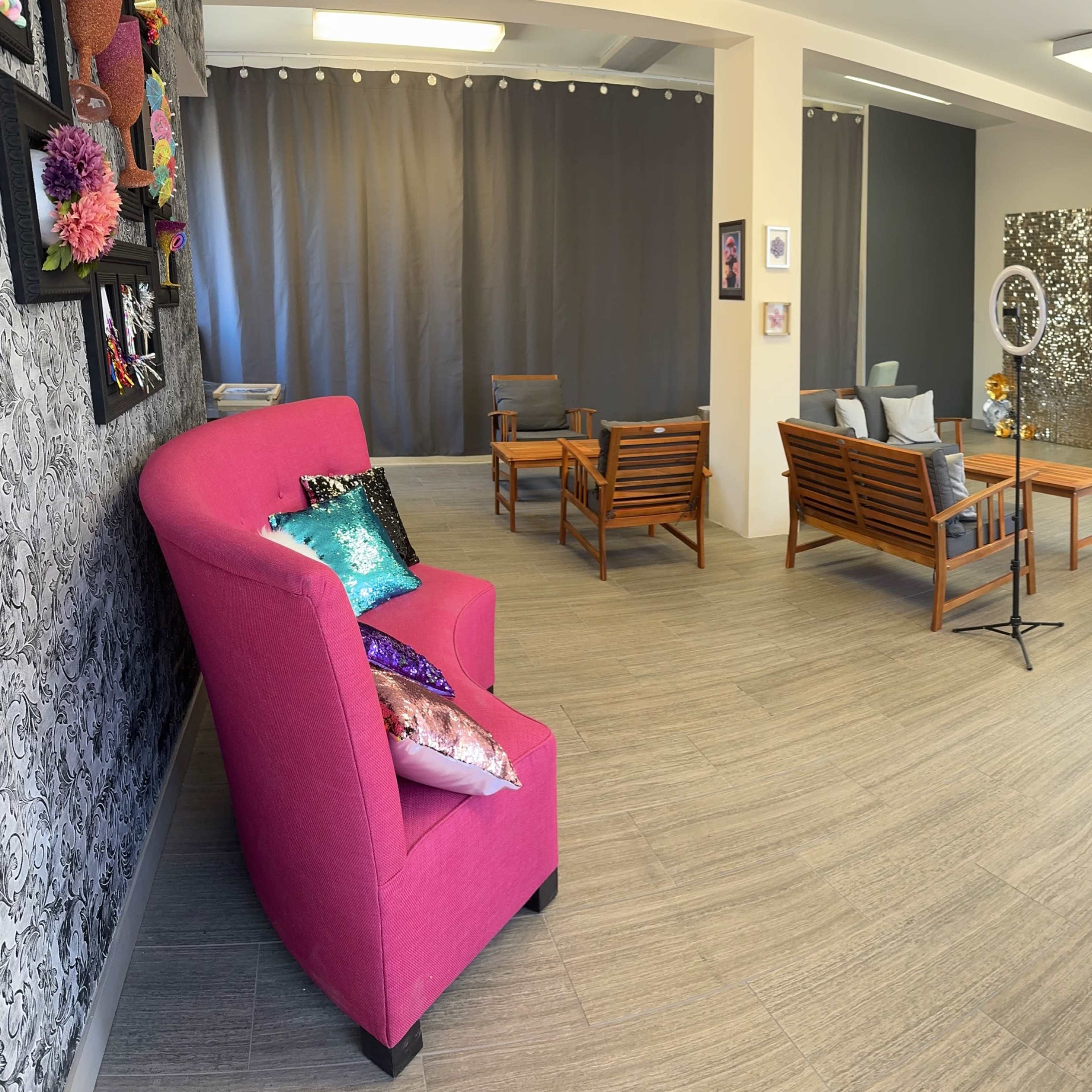 A well-lit, modern room with wooden seating, a pink armchair, and decorative wall art.