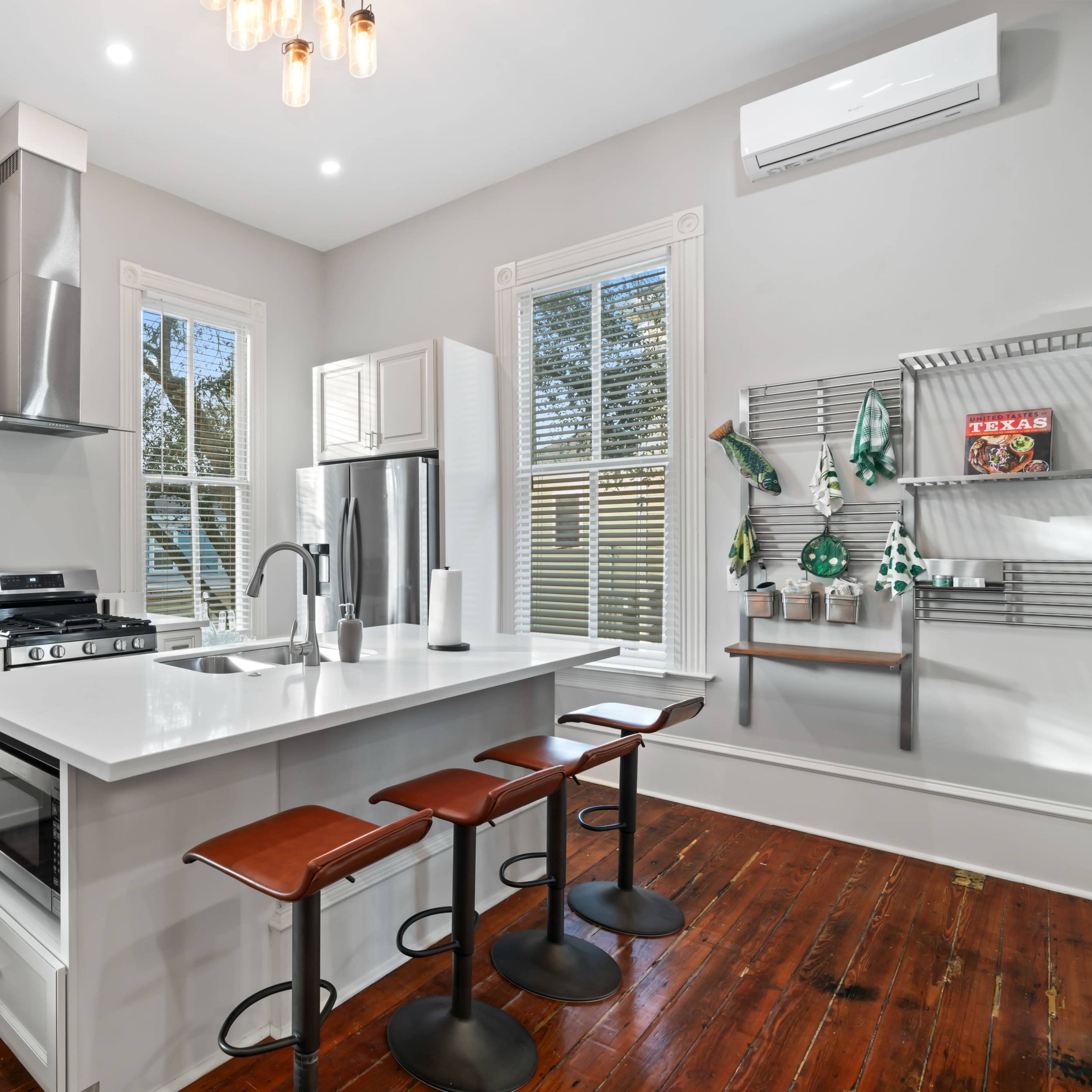 A modern kitchen features stainless steel appliances, a large central island with seating, and multiple windows allowing natural light to illuminate the space.